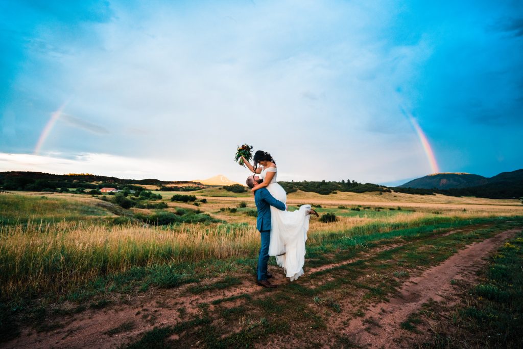 Couple celebrating their marriage under a rainbow during their Larkspur Elopement