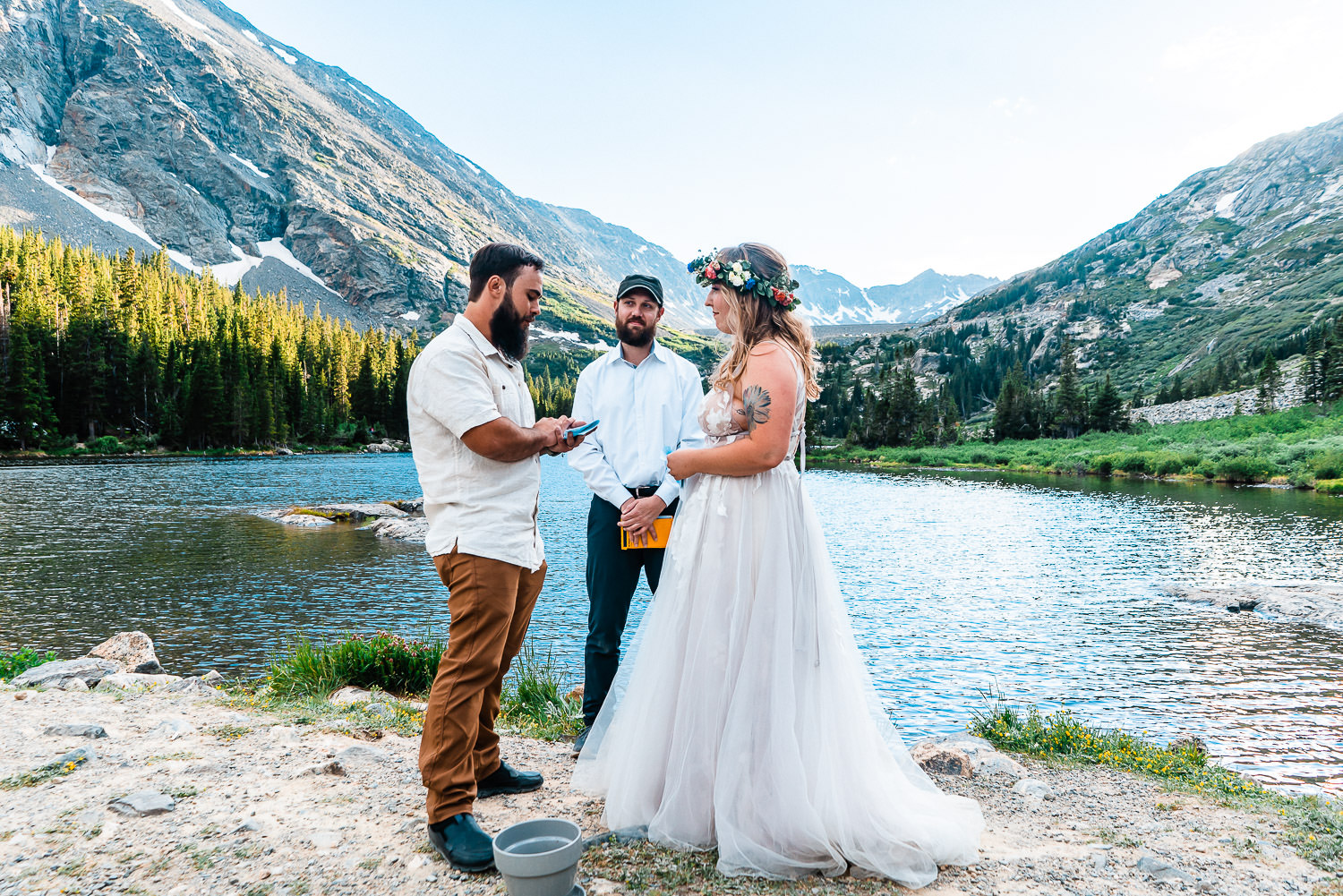 bride and groom exchange vows with as their officiant looks on at Blue Lakes Colorado 