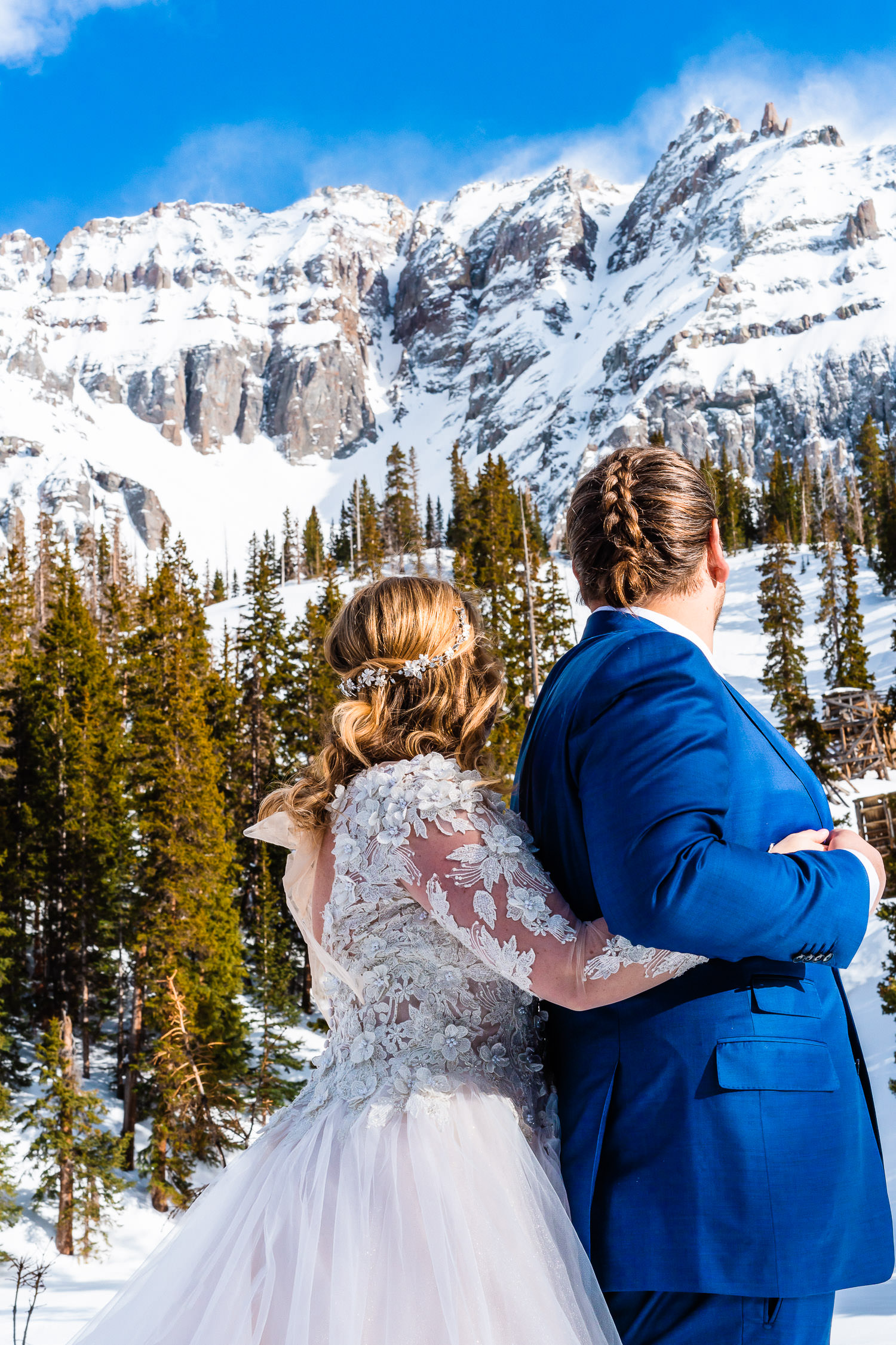 newlyweds looking at a snow covered mountain