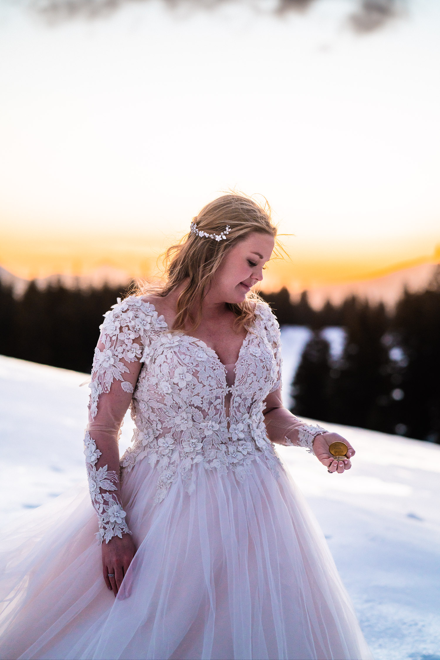 newly wed bride holds a sentimental pocket watch on a snow covered mountain