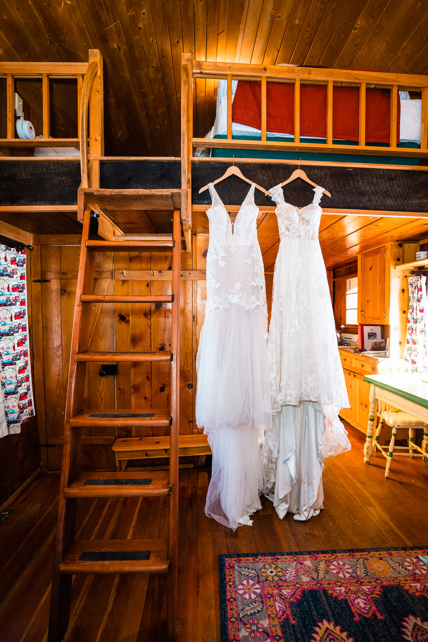 Two wedding dresses hanging side by side in a cozy mountain cabin