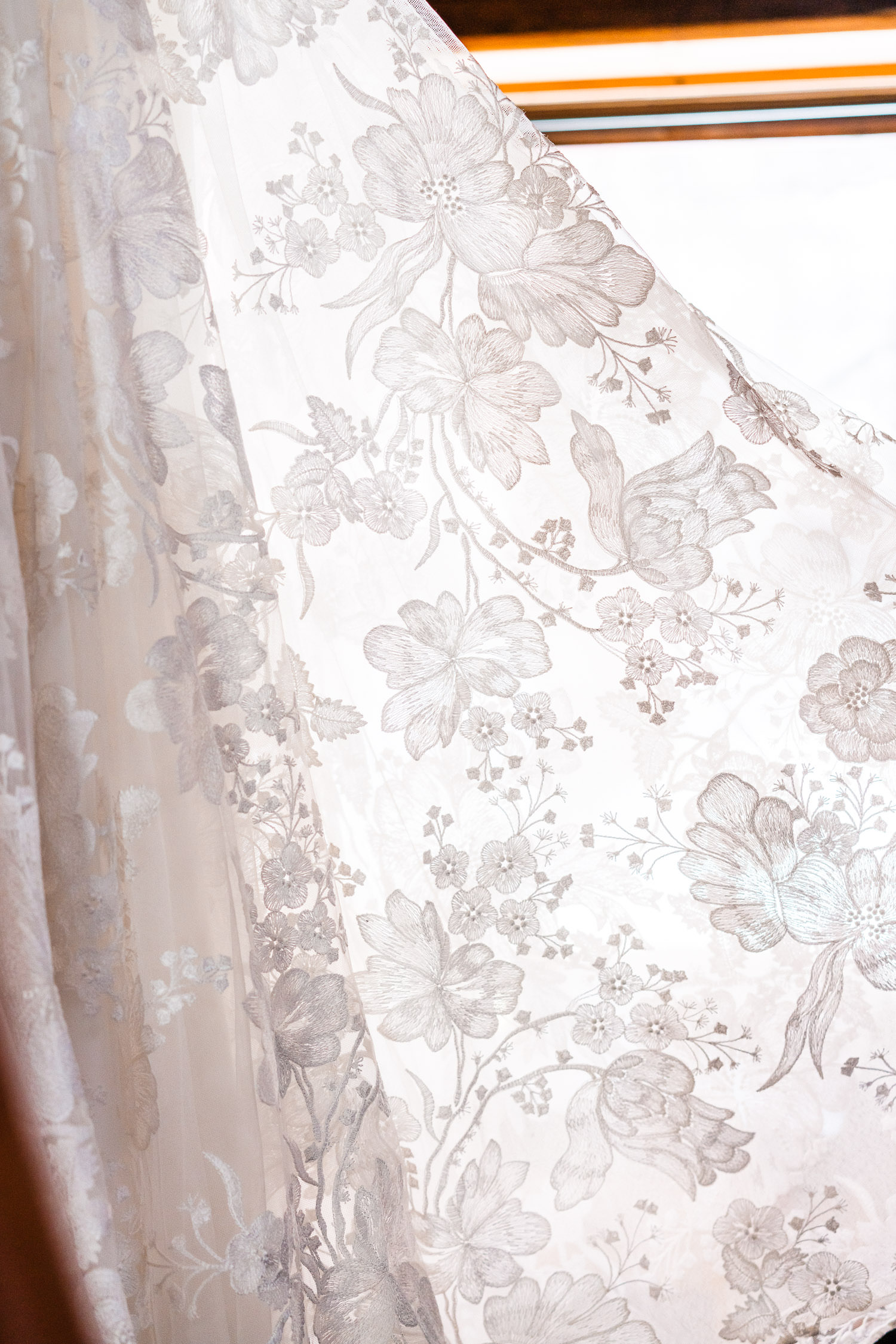 Natural light cascading through the floral fabric of a wedding dress