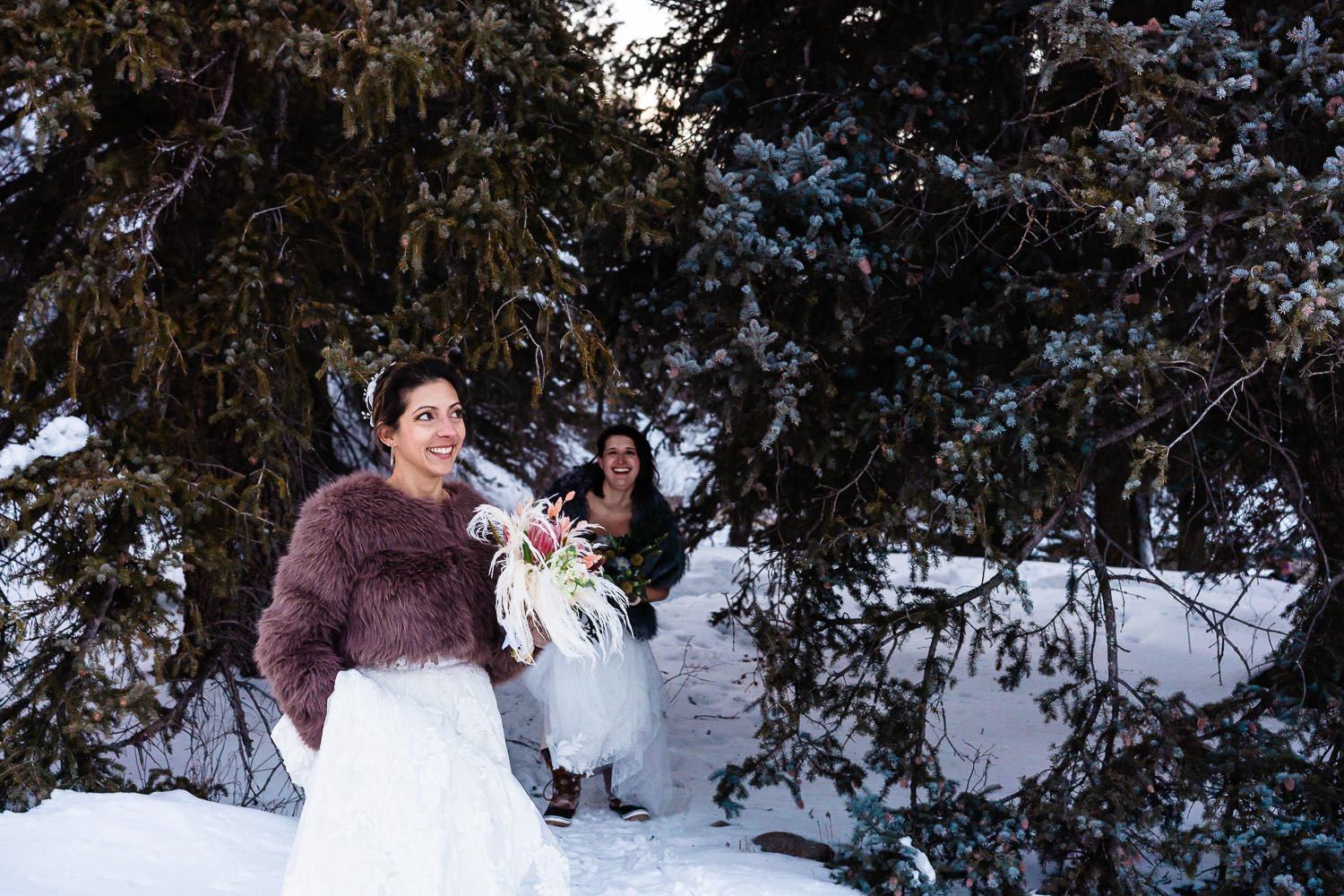 lesbian newlyweds hiking through a snowy forest