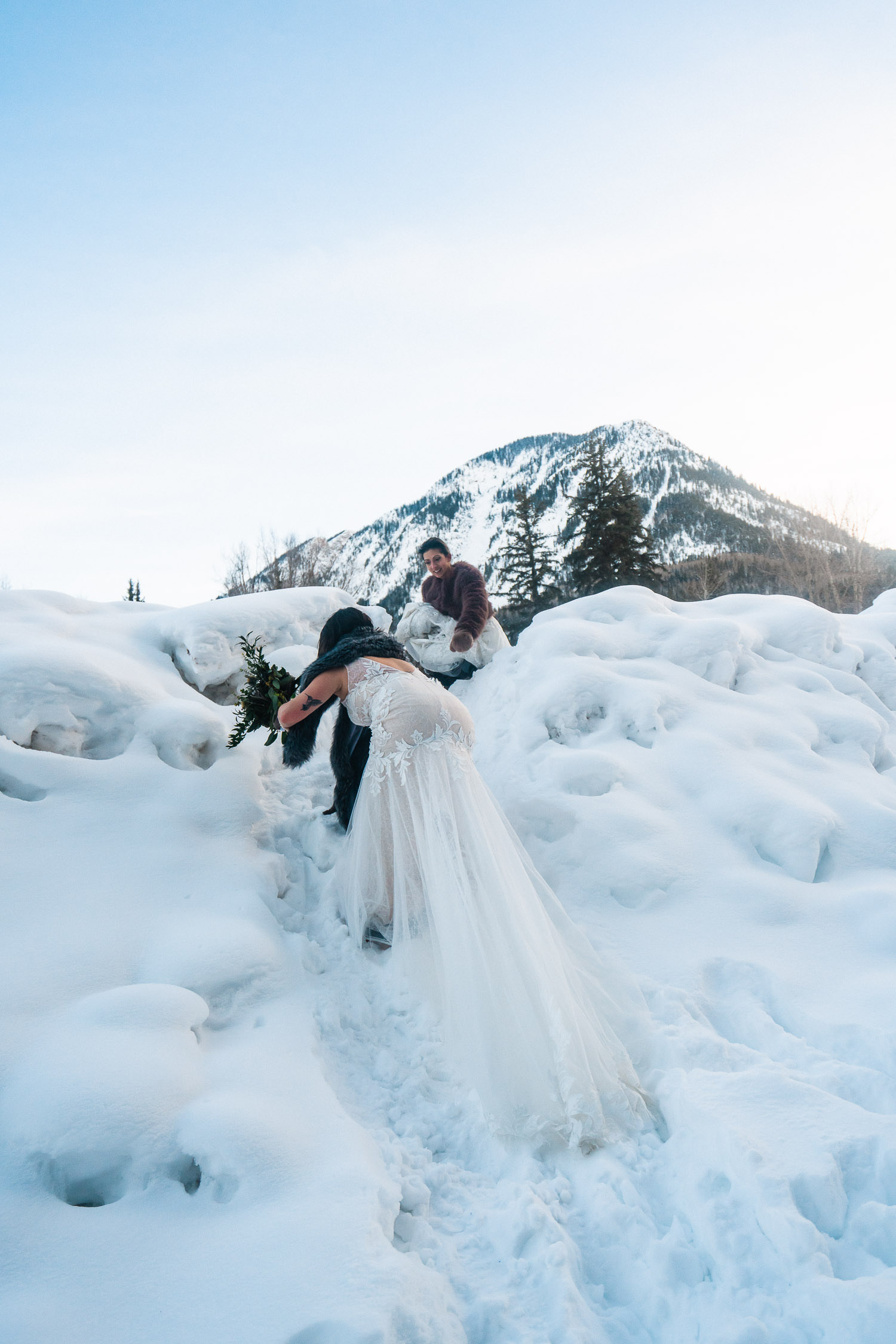 two brides climbing over mounds of snow