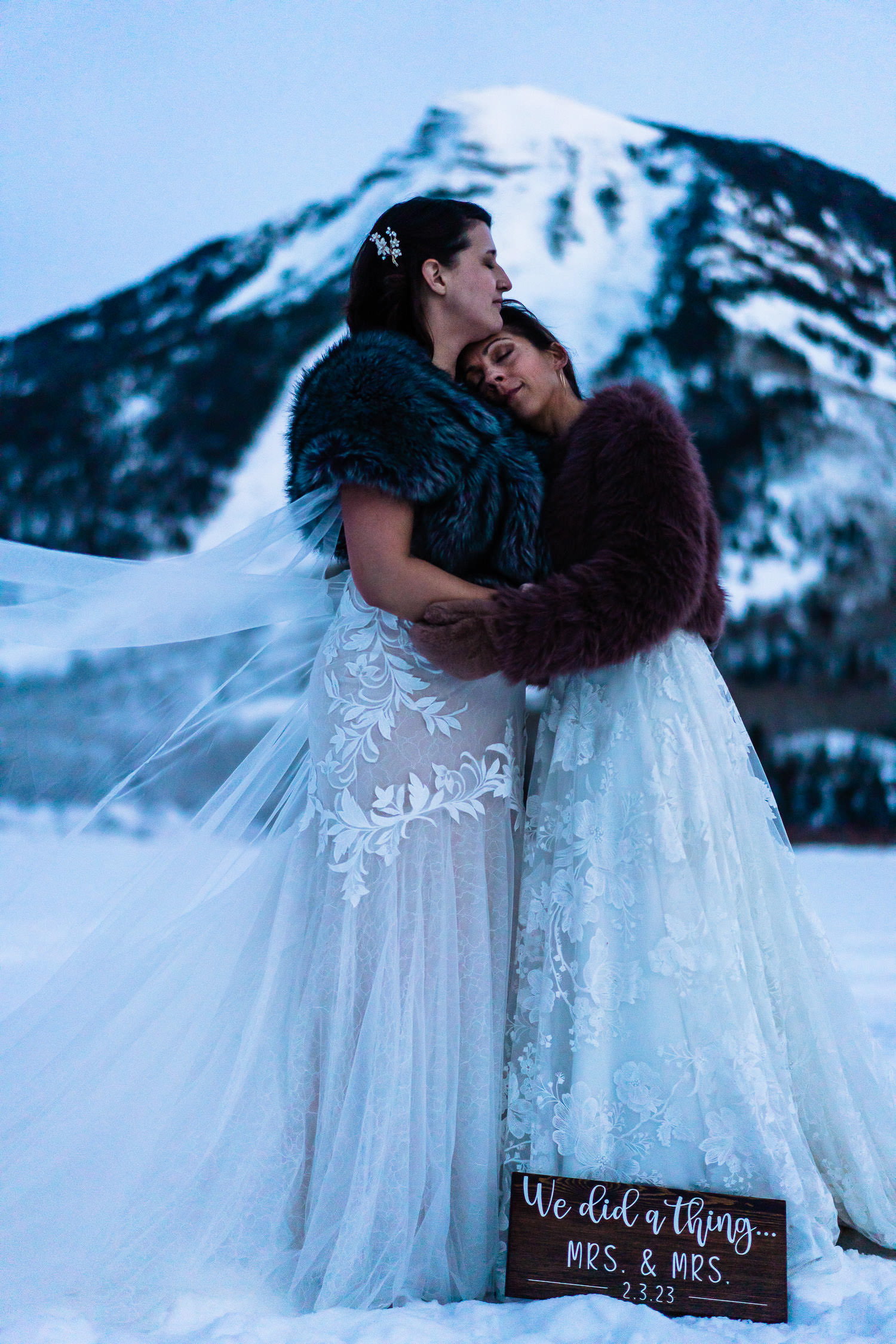 newlywed brides snuggling near a snowy mountain