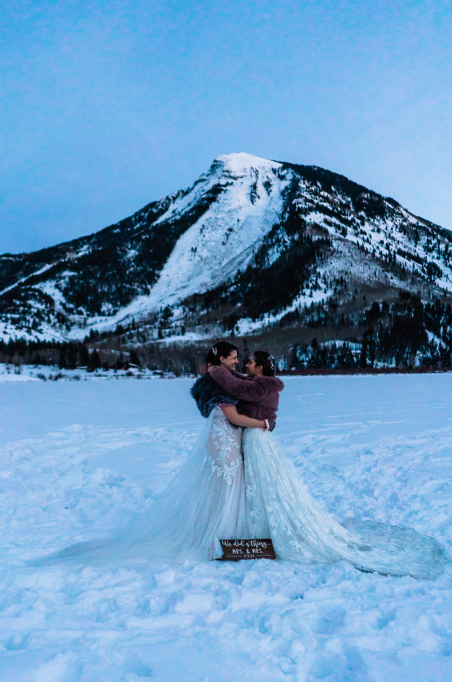 newlywed brides snuggling near a snowy mountain