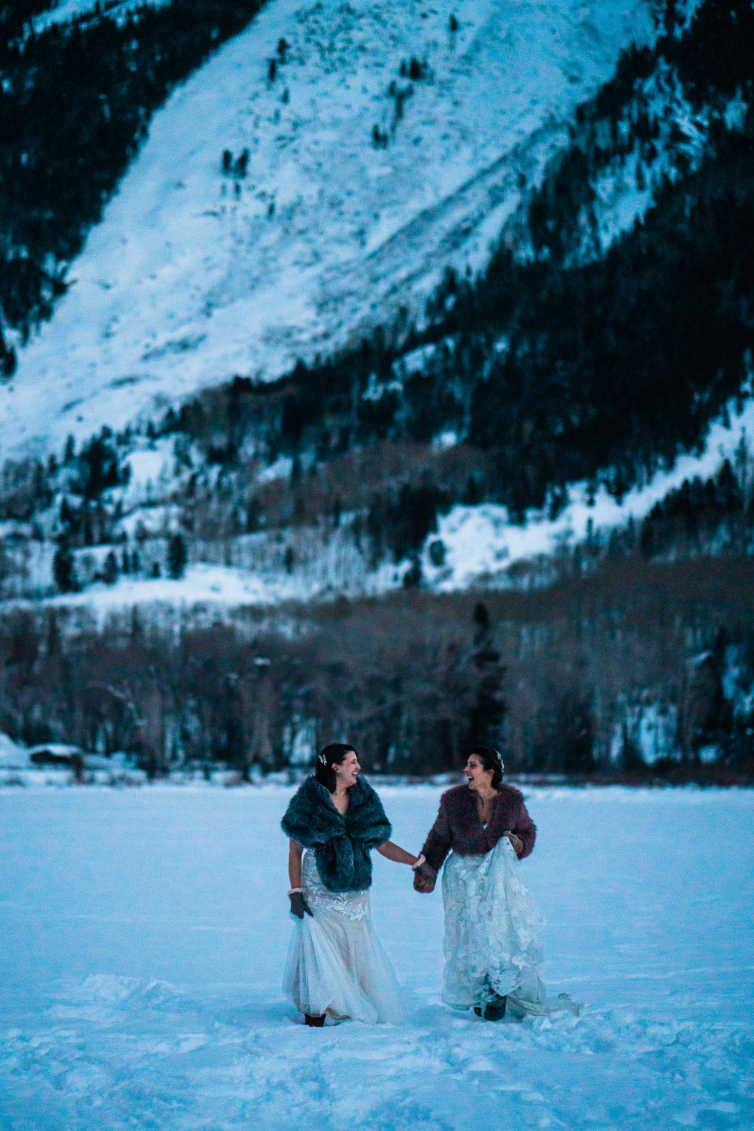 lesbian brides skipping through a snowy field