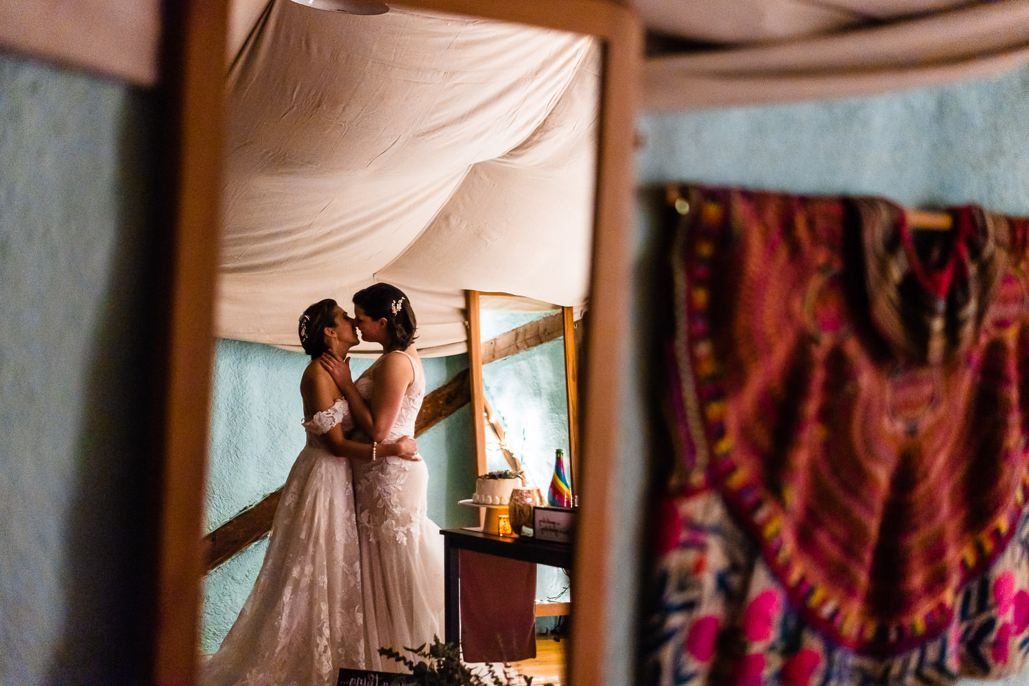newlywed brides sharing a sweet kiss in the mirror