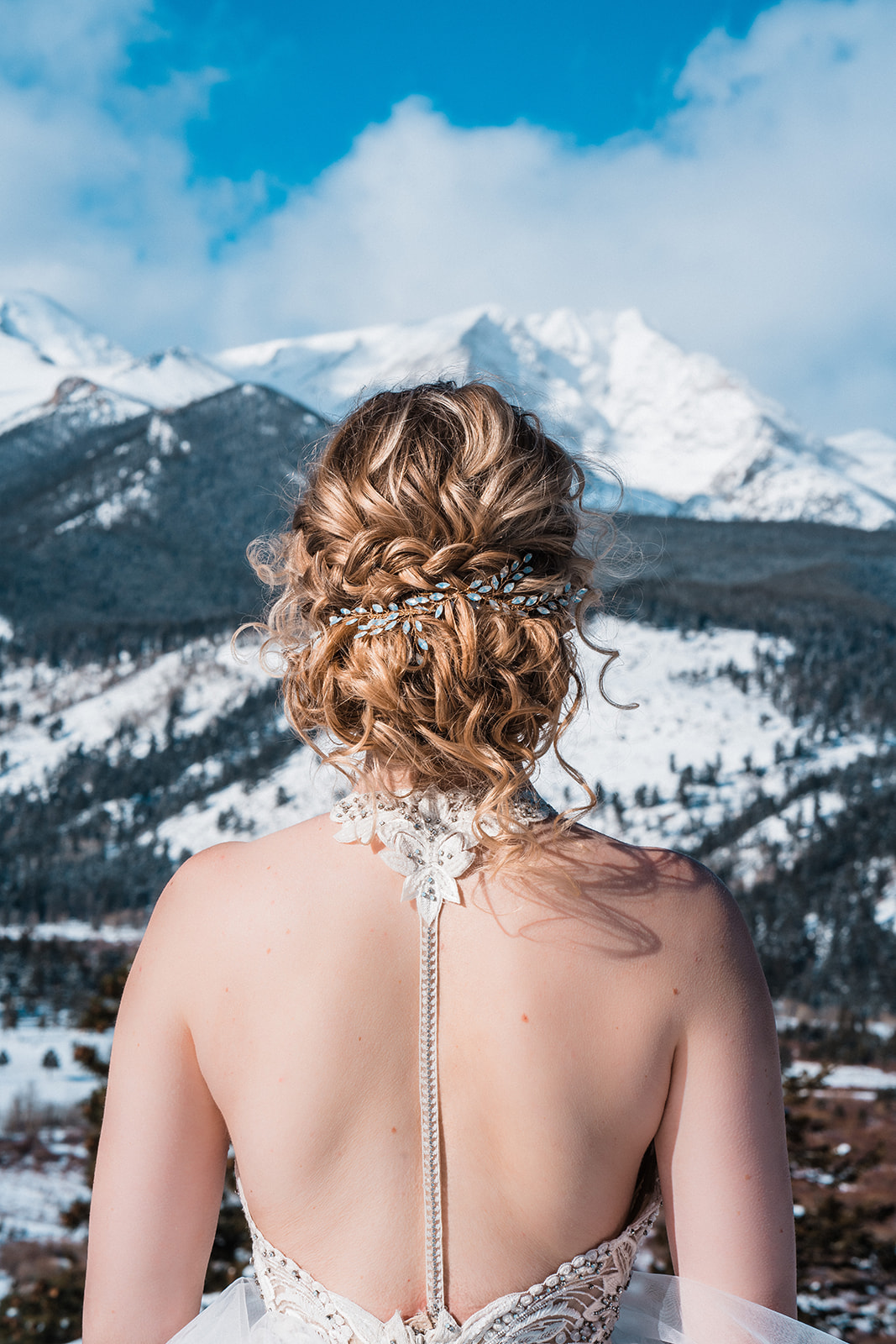 bride with her hair done overlooking a snowy mountain range during her Colorado winter elopement guide