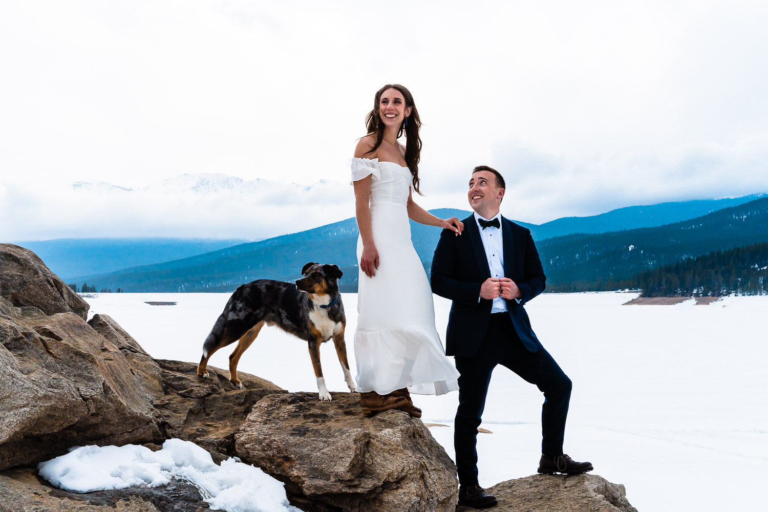 newlyweds on boulders during their snowy winter elopement