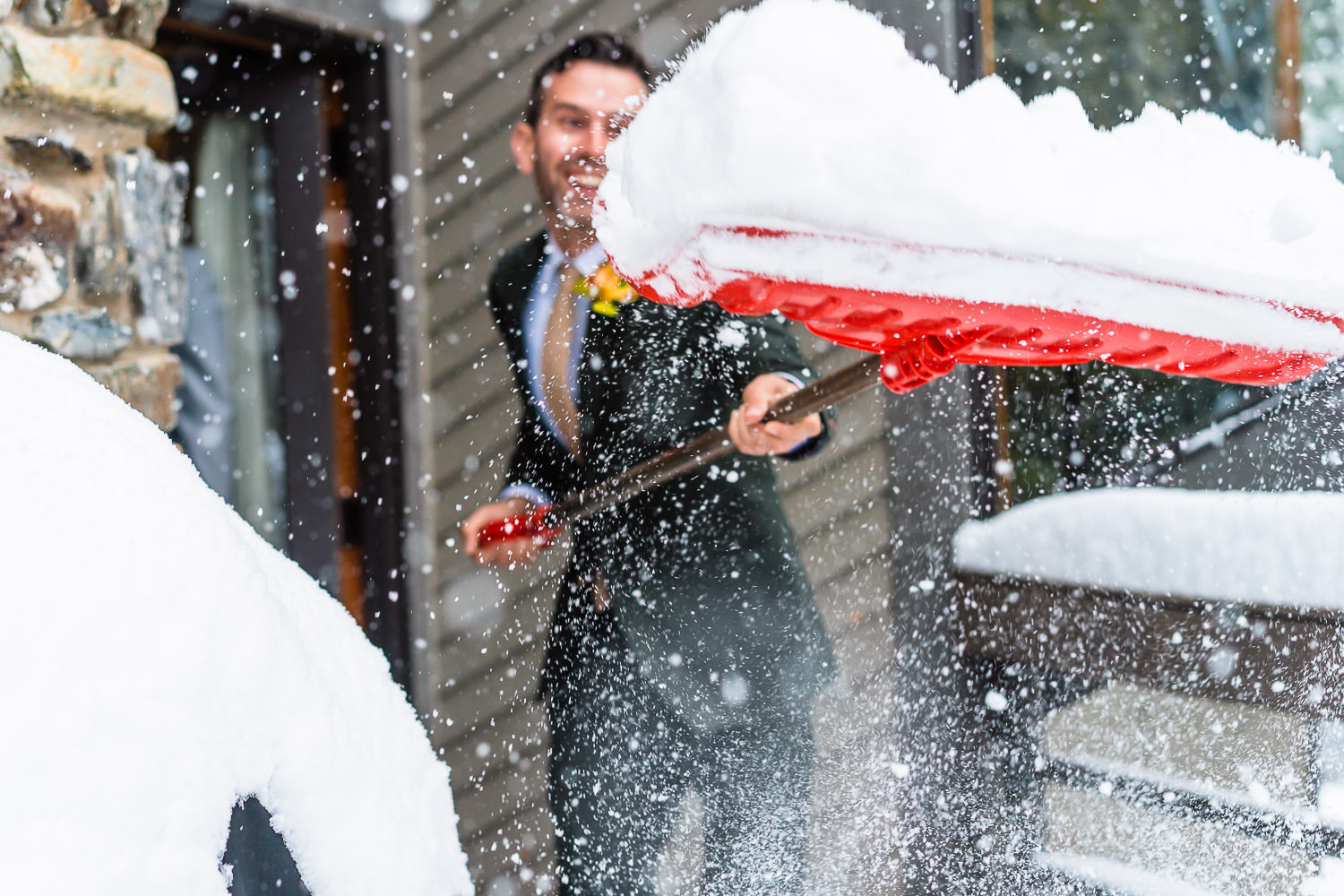 groom shoveling snow during his Colorado winter elopement