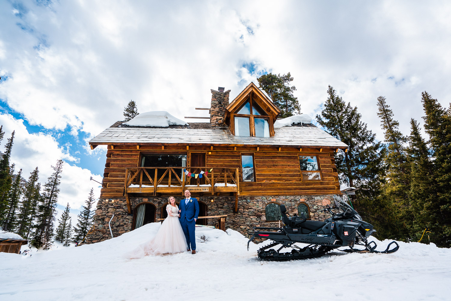 newlyweds at their cabin rental with their snowmobile during their winter elopement in Colorado