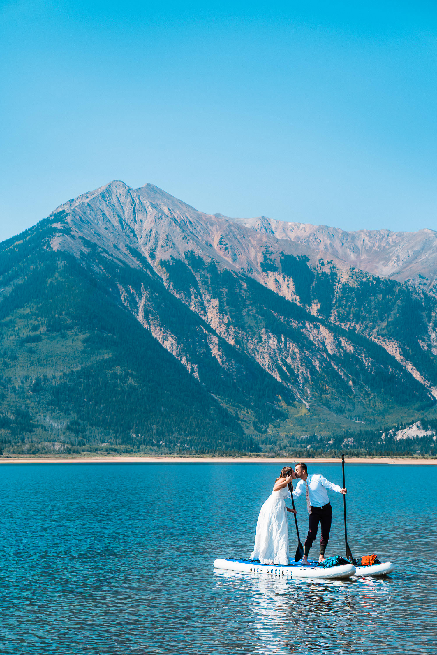 newlyweds kiss on standup paddle boards atop Twin Lakes during their Buena Vista elopement
