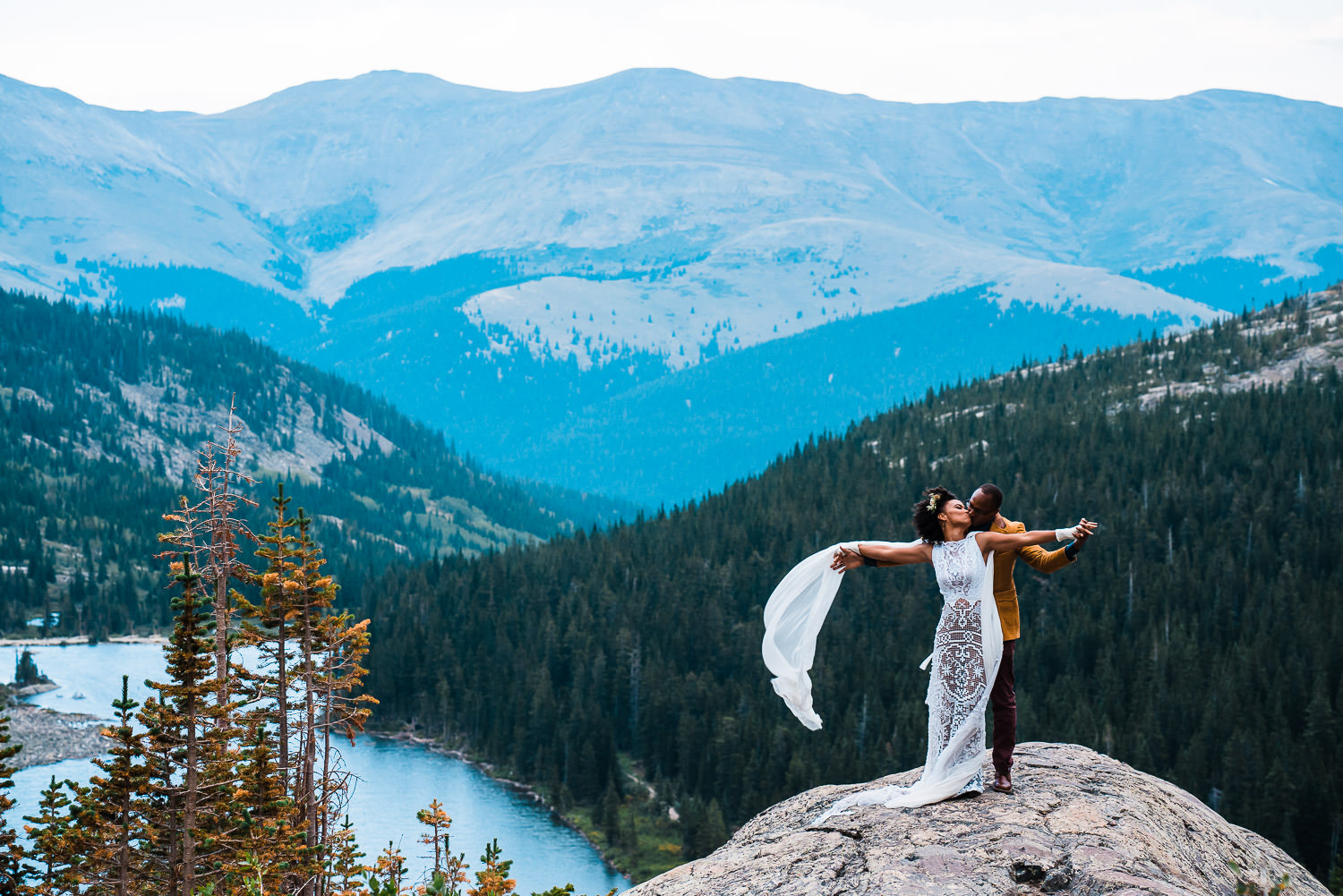 Bride and groom kissing atop a mountain overlooking a lake in Breckenridge Colorado