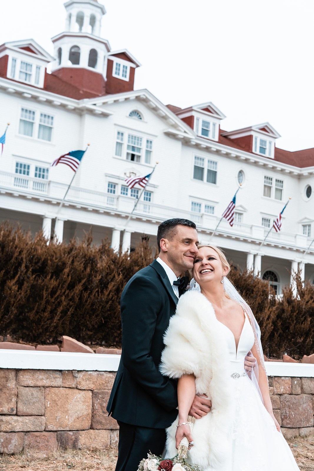 Beautiful bride and groom posing smiling at one another in front of the Stanley Hotel in Estes Park