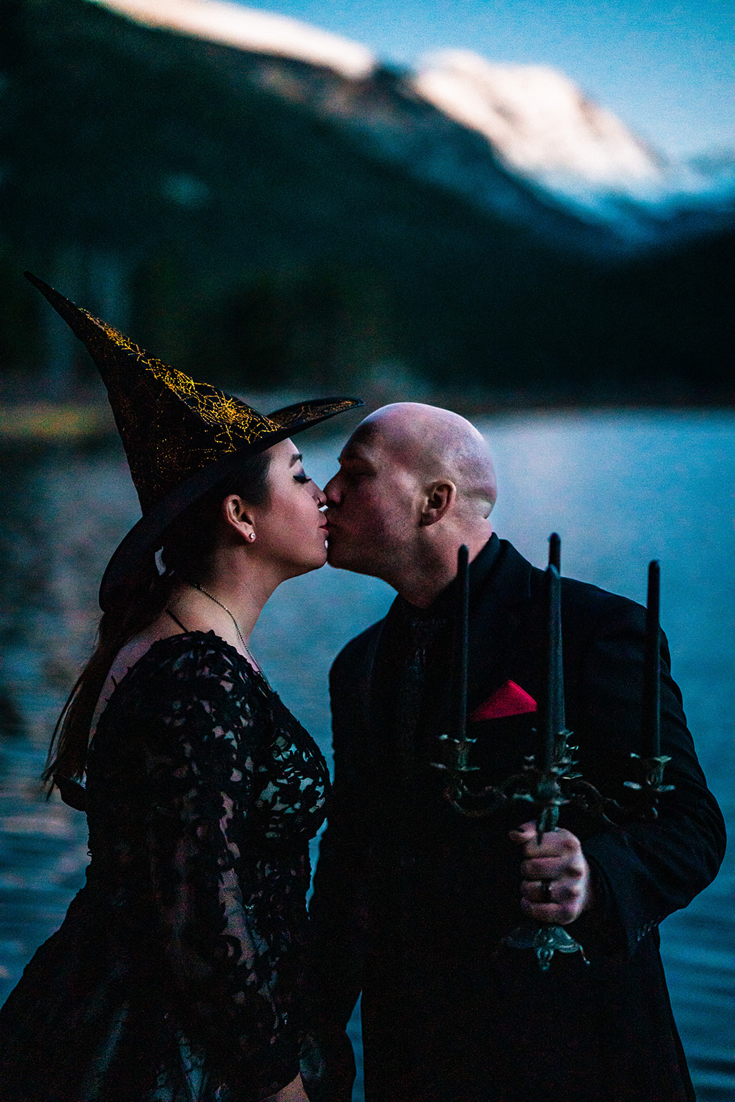 Beautiful bride and groom in spooky attire, a witches hat and holding a candlelabra