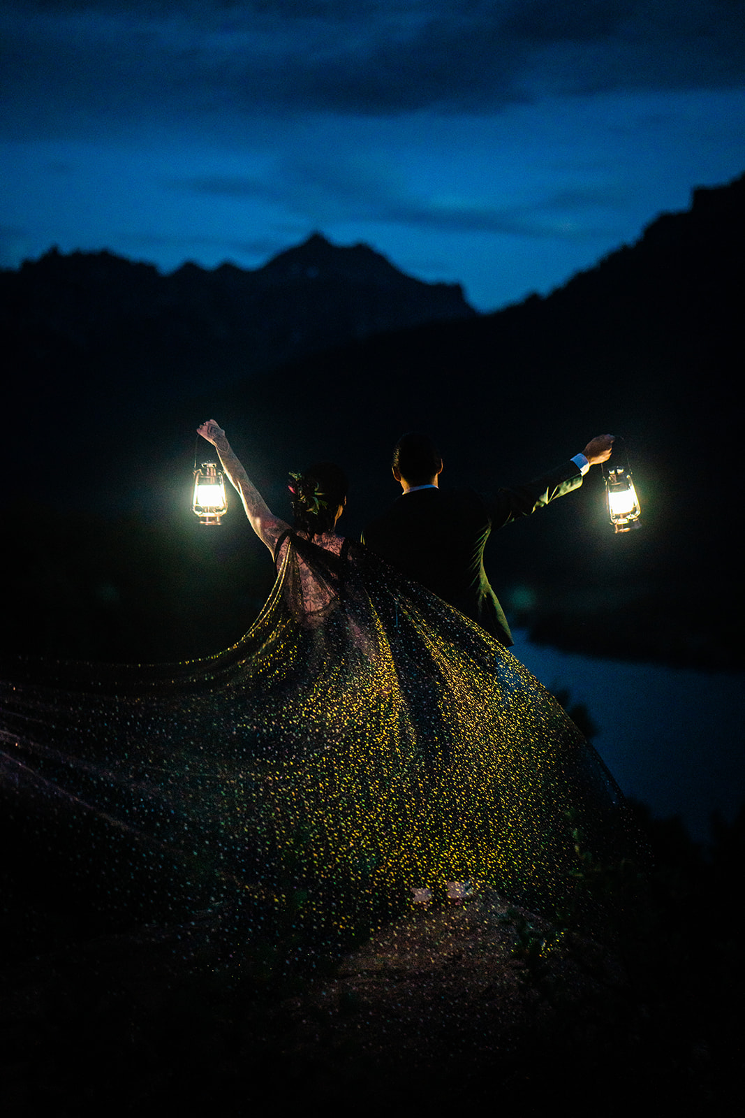 Bride and groom holding lanterns up at night