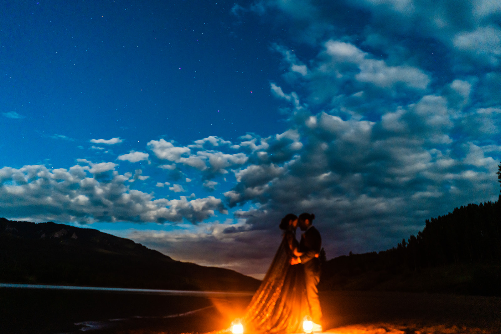 Bride and groom kissing near a fire