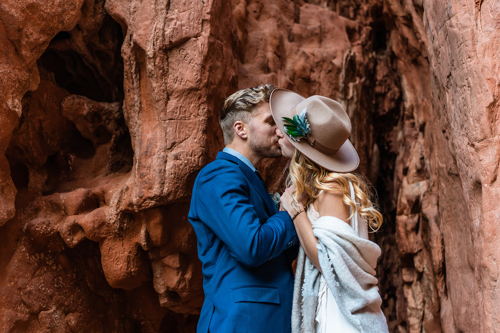newly engaged couple kissing beneath towering red rock formations in Garden of the Gods