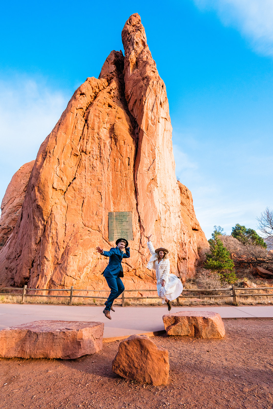 Newly engaged couple jumping in the air in frnot of bright red rocks