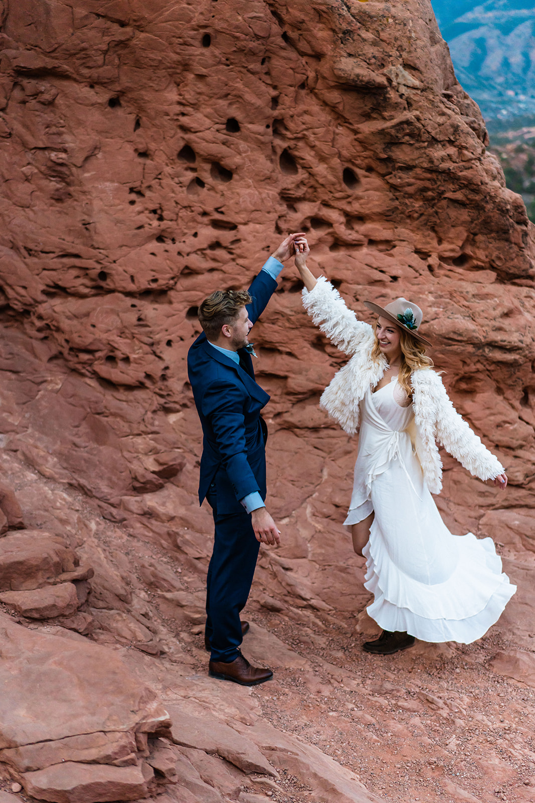 Newly engaged couple dancing in front of bright red rocks