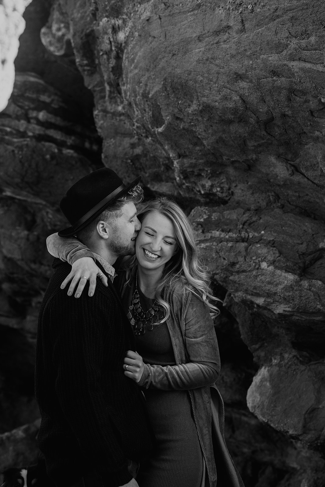 stylish fiancée kissing his partners cheek in black and white photo