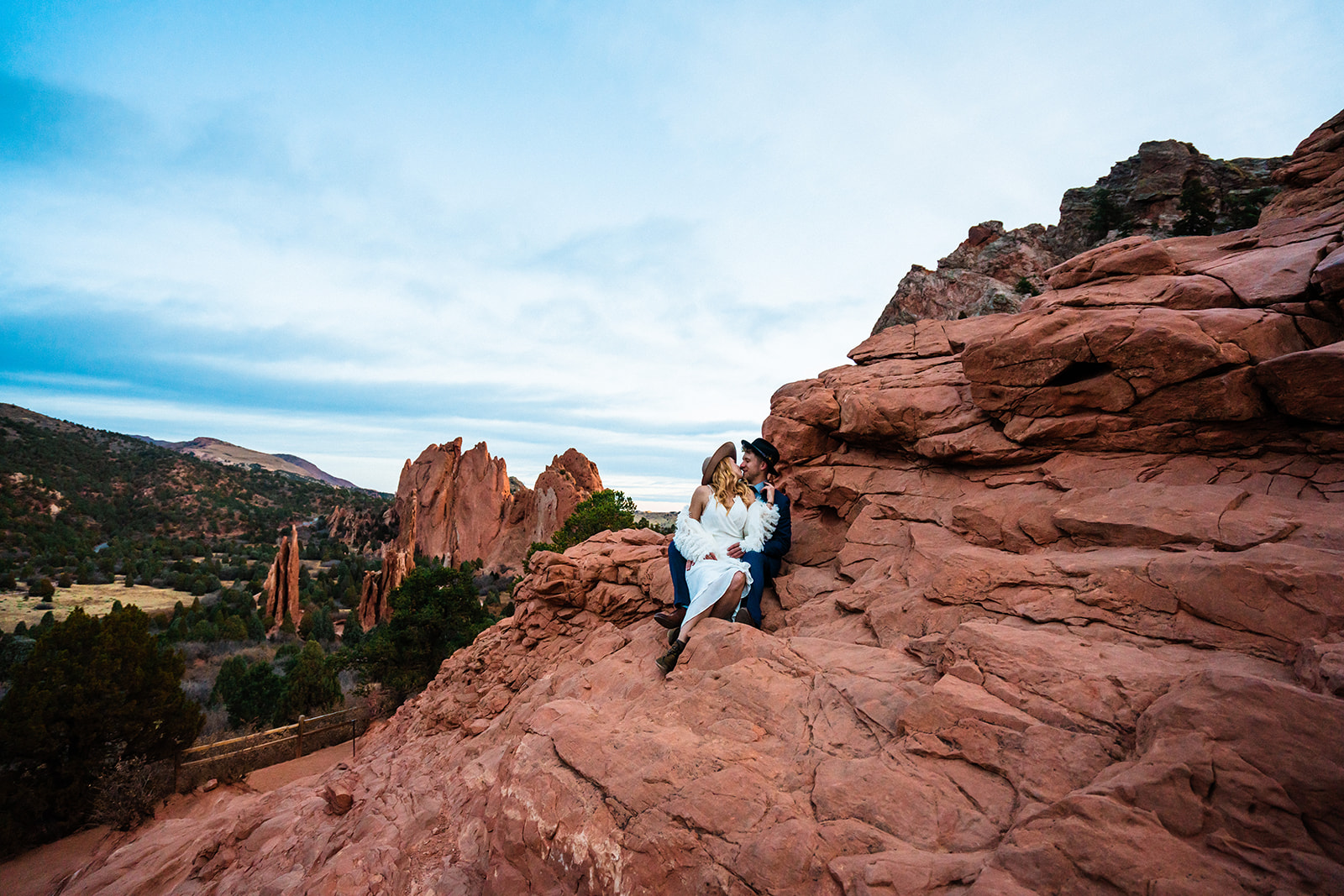 Newly engaged couple sitting in front of bright red rocks