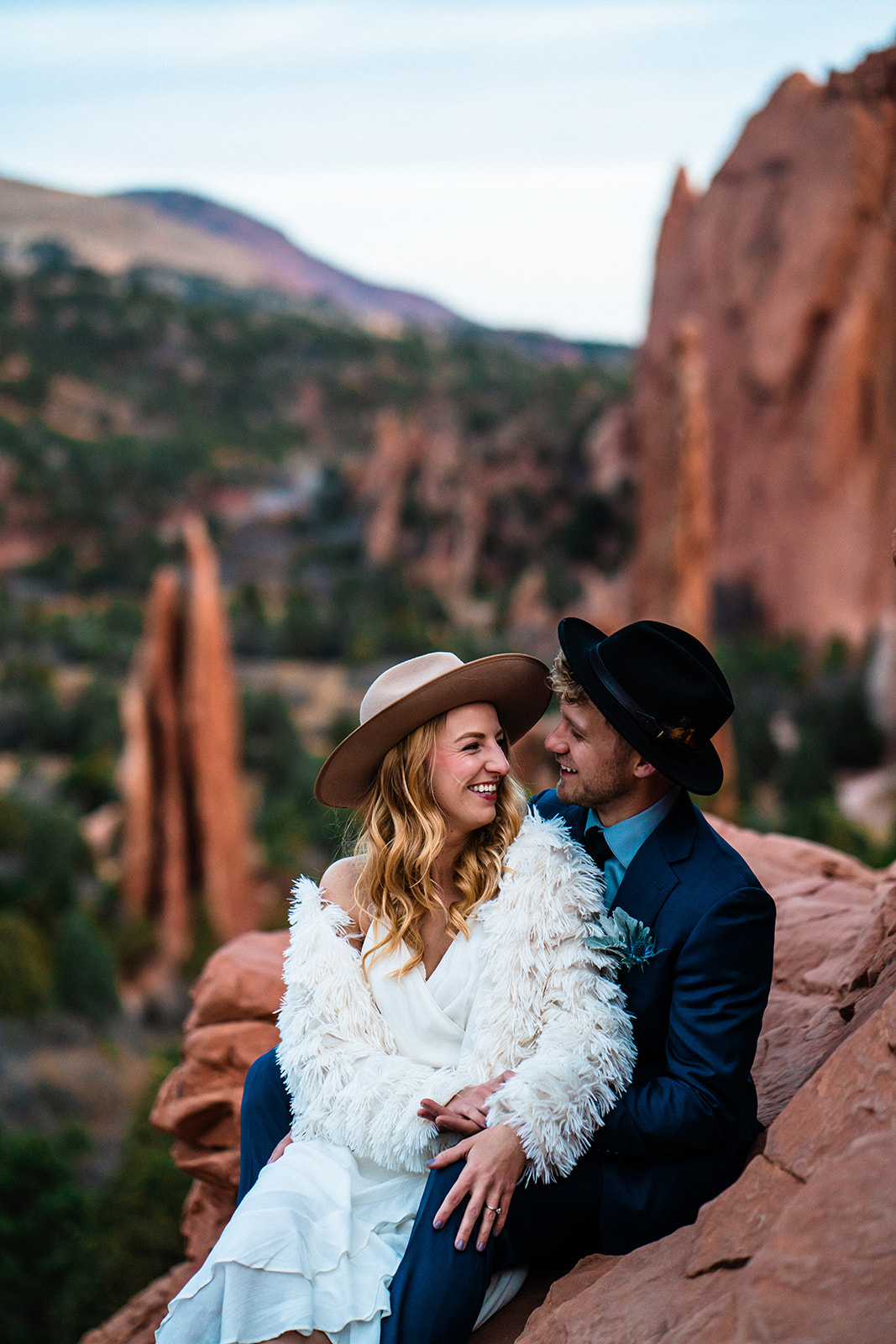 Newly engaged couple sitting in front of bright red rocks at the Garden of the Gods