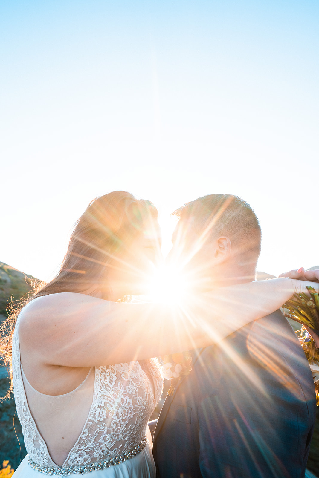 Black and white photo of bride and groom hugging during sunrise