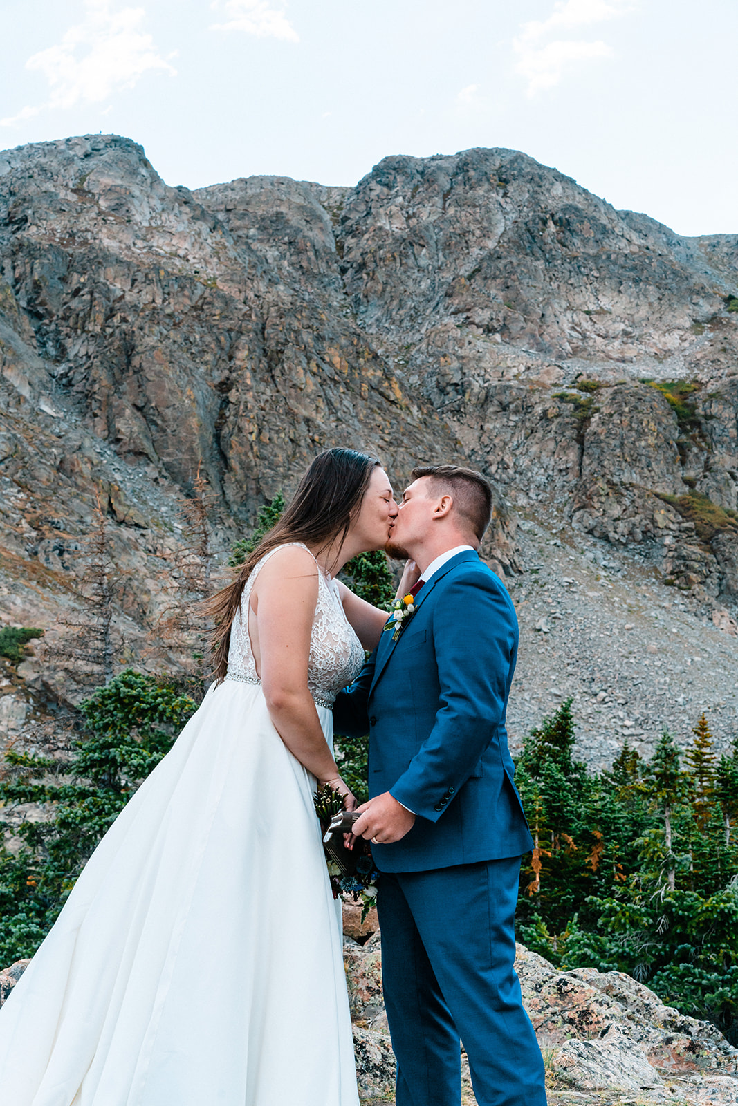 Bride and groom kissing at alpine lake