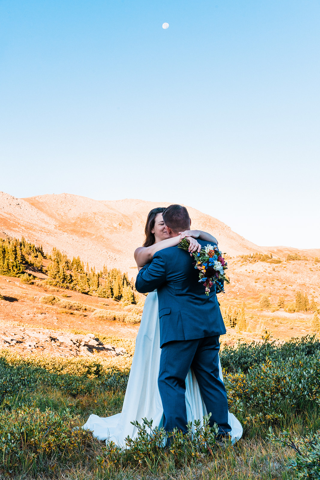 Bride and groom hugging at an Alpine lake