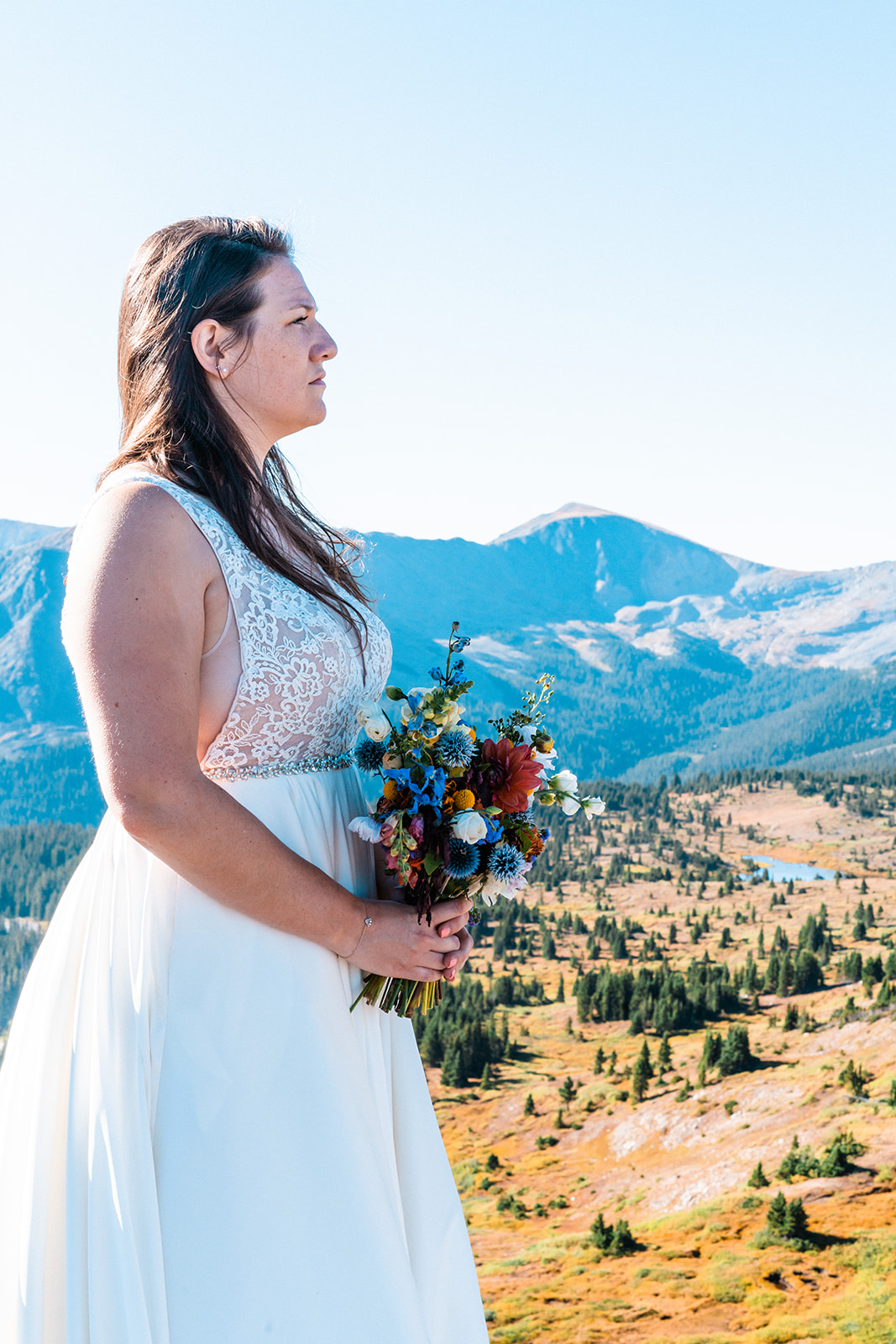 Beautiful bride looking off into the distance holding a colorful bridal bouquet