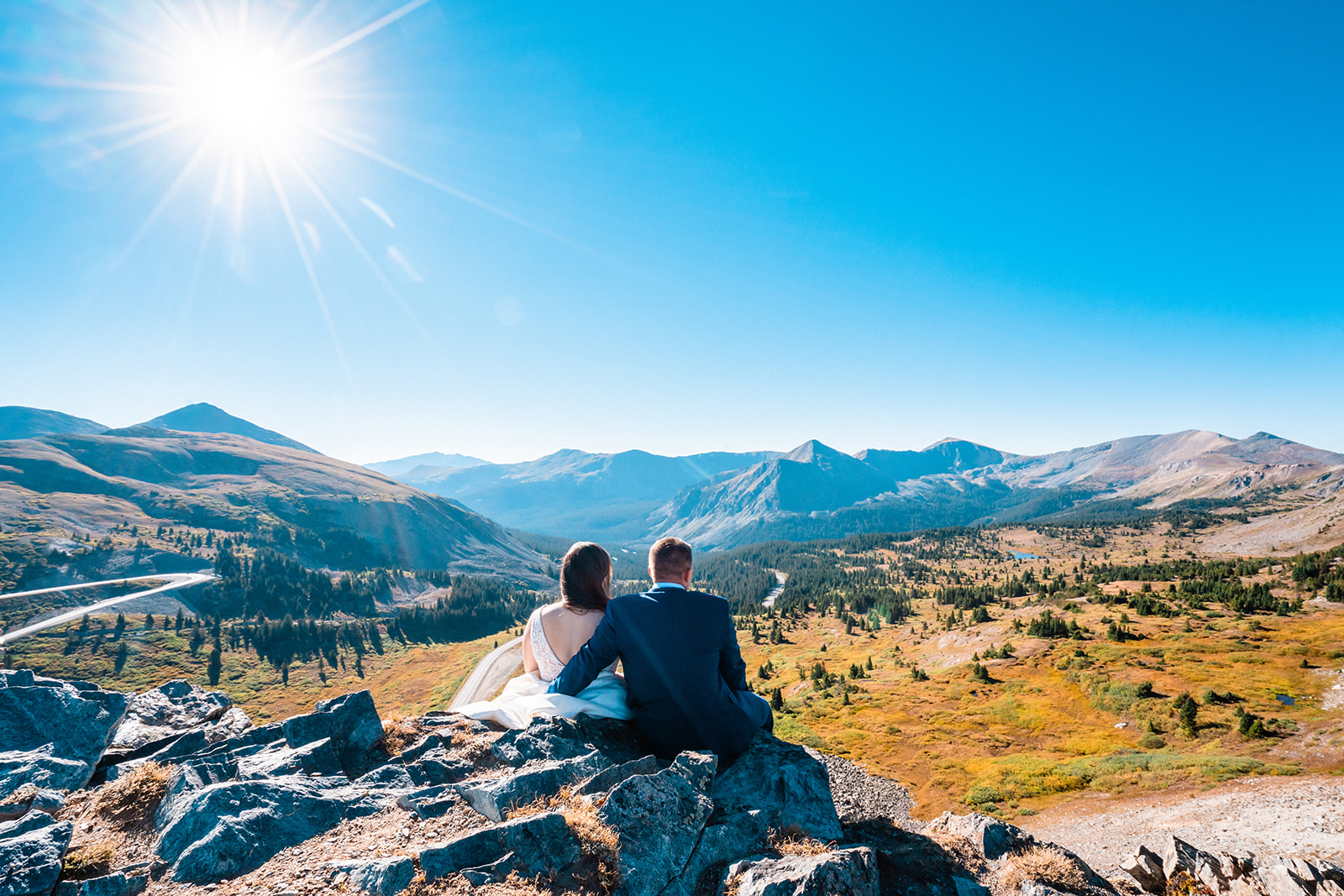 Bride and groom sitting on rocks in the Colorado mountains