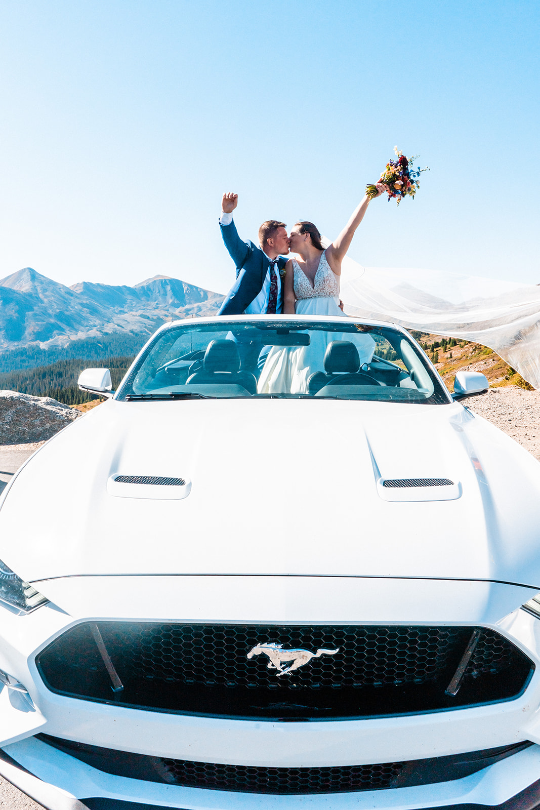 Bride and groom posing in a sports car
