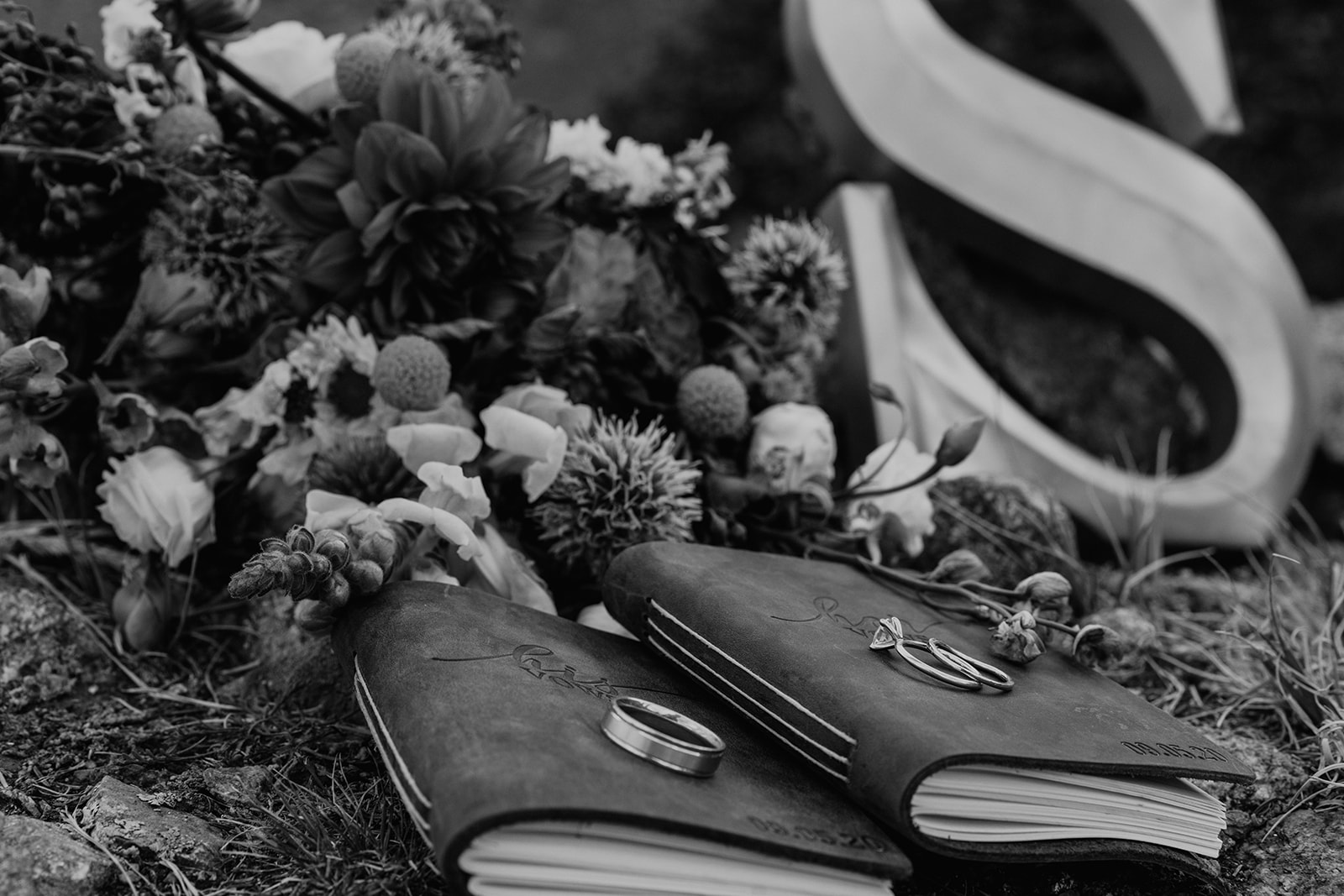 Black and white photo of Bride and groom vow books, flowers, and details