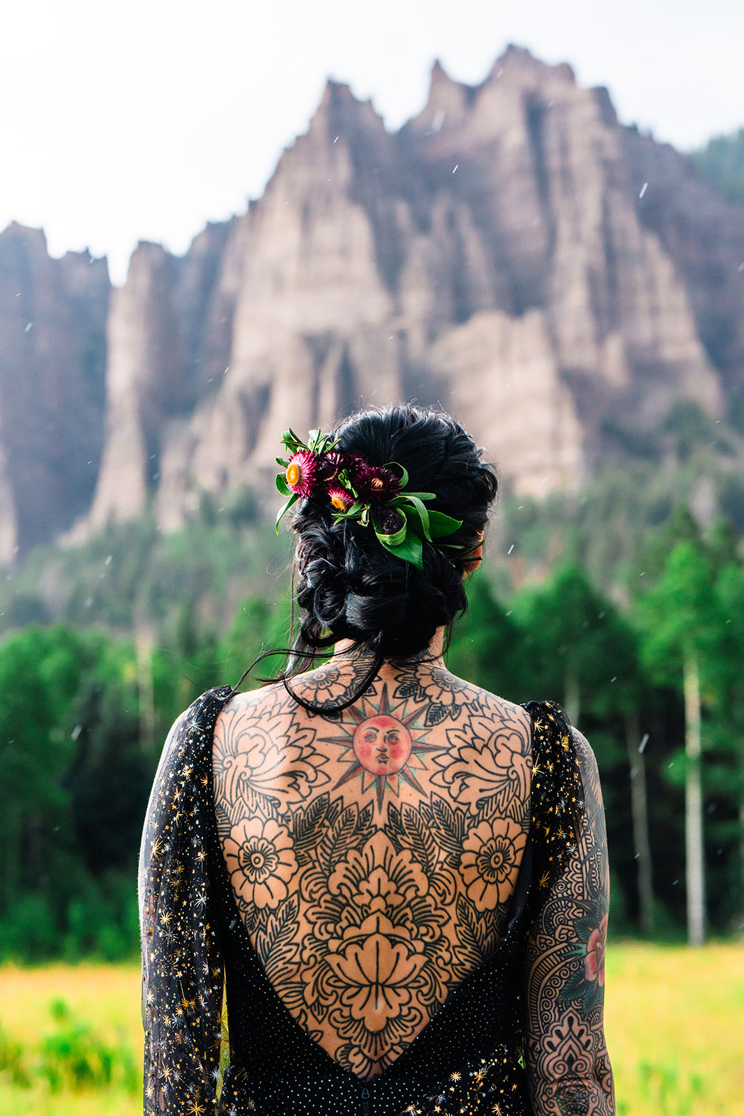 Bride in a black backless dress showing her back tattoos