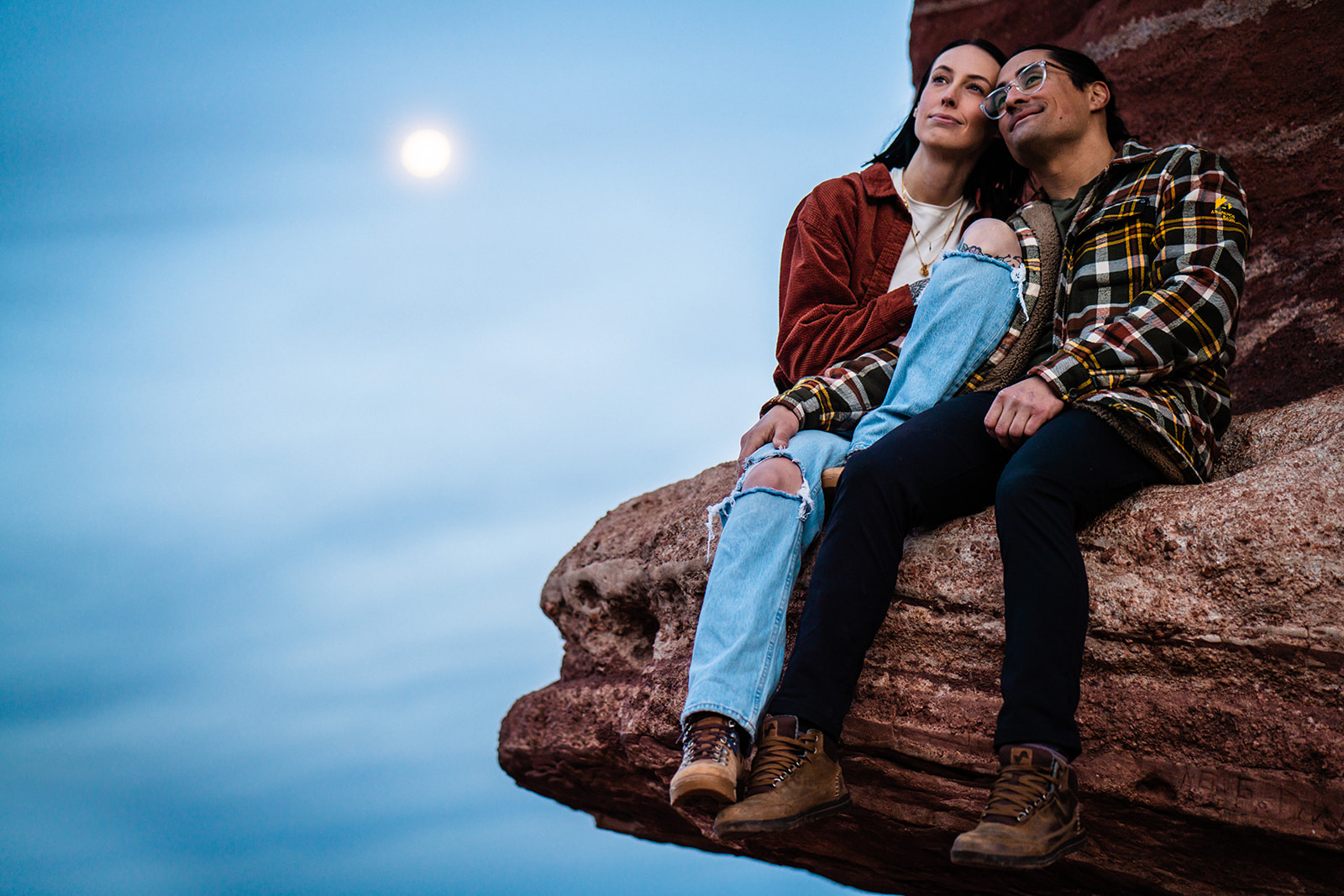Newly engaged couple sitting on rock formation at the garden of the gods