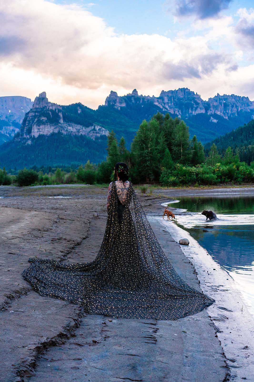 Bride in a stunning black elopement dress standing near lake
