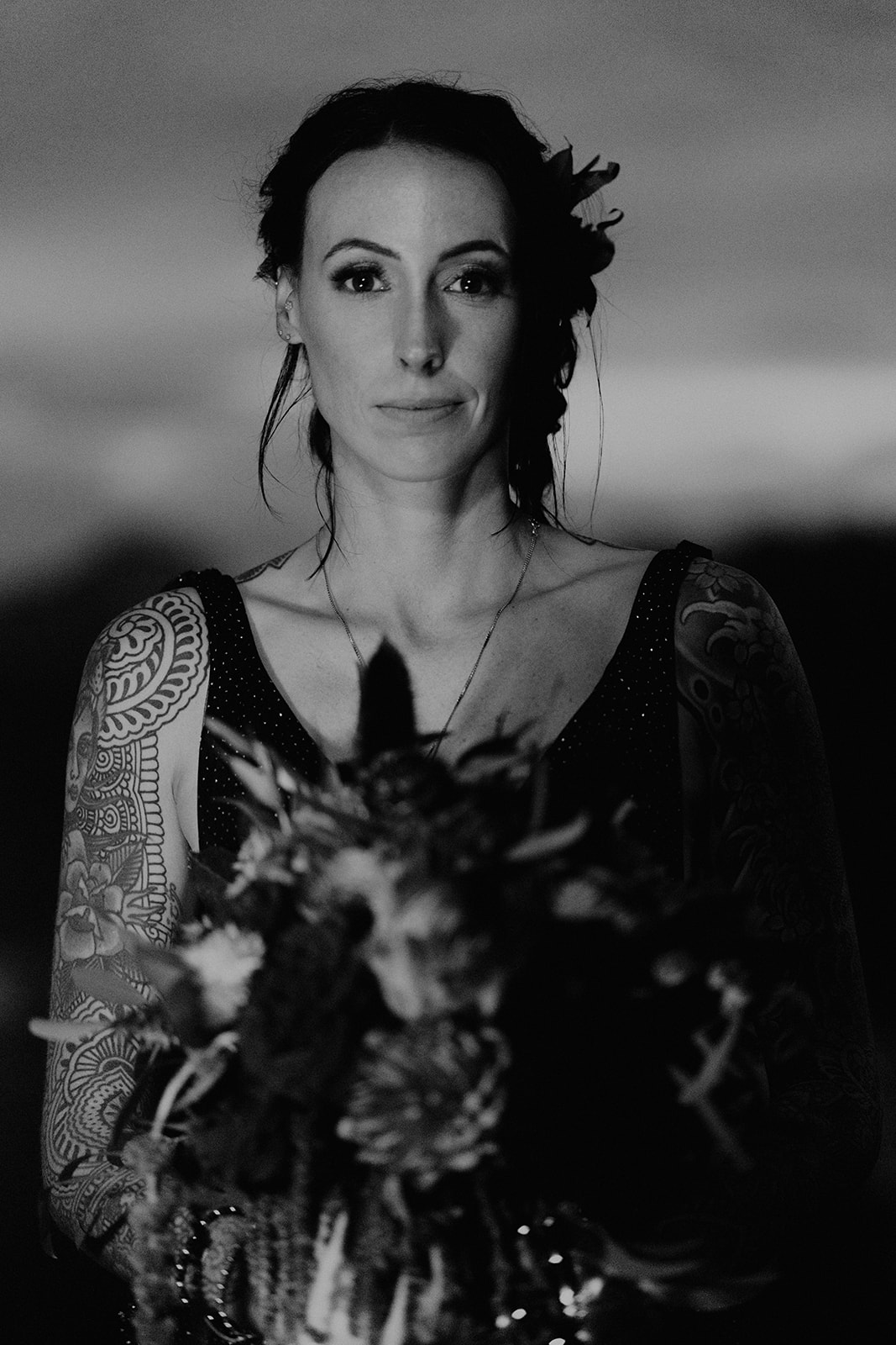 Black and white photo of Beautiful bride holding a colorful bouquet full of red and pink florals during her celestial themed elopement