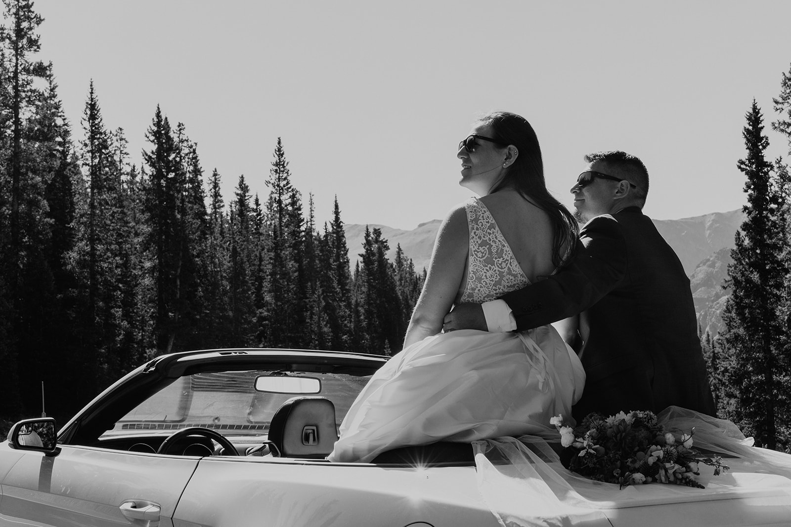 Black and white photo of bride and groom sitting in sports car