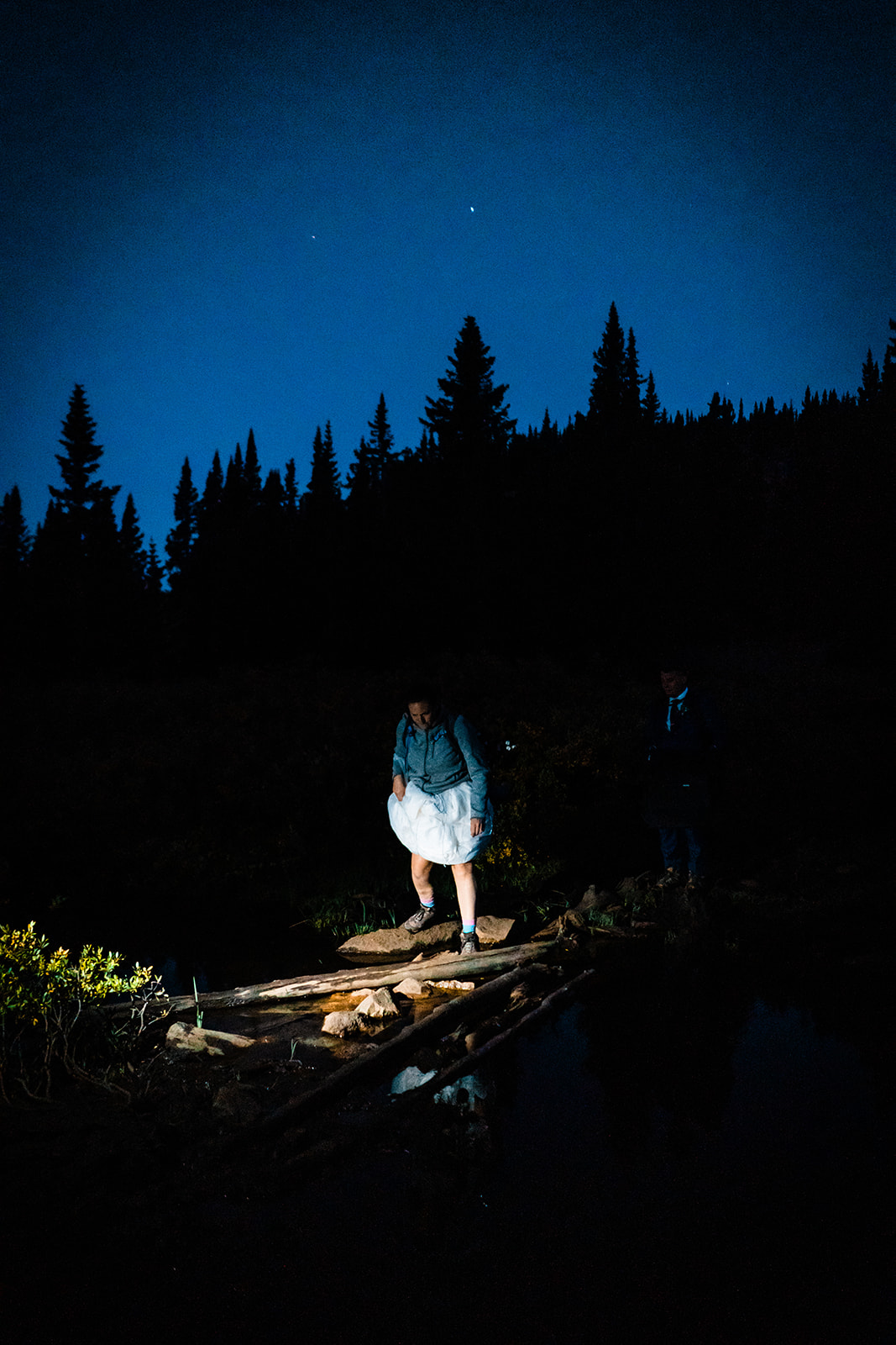 Bride and groom hiking down the Colorado mountains at night
