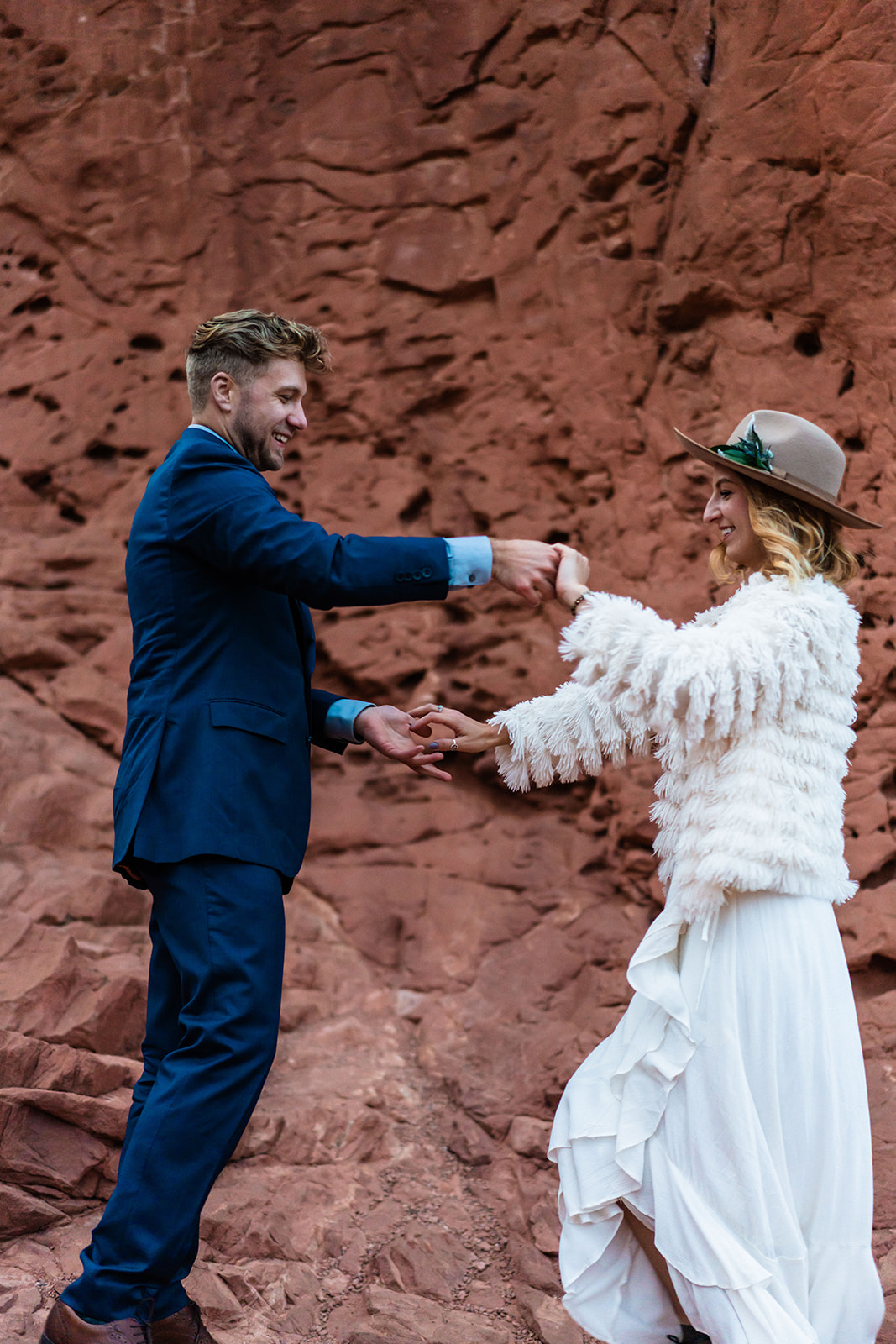 Newly engaged couple dancing in front of bright red rocks