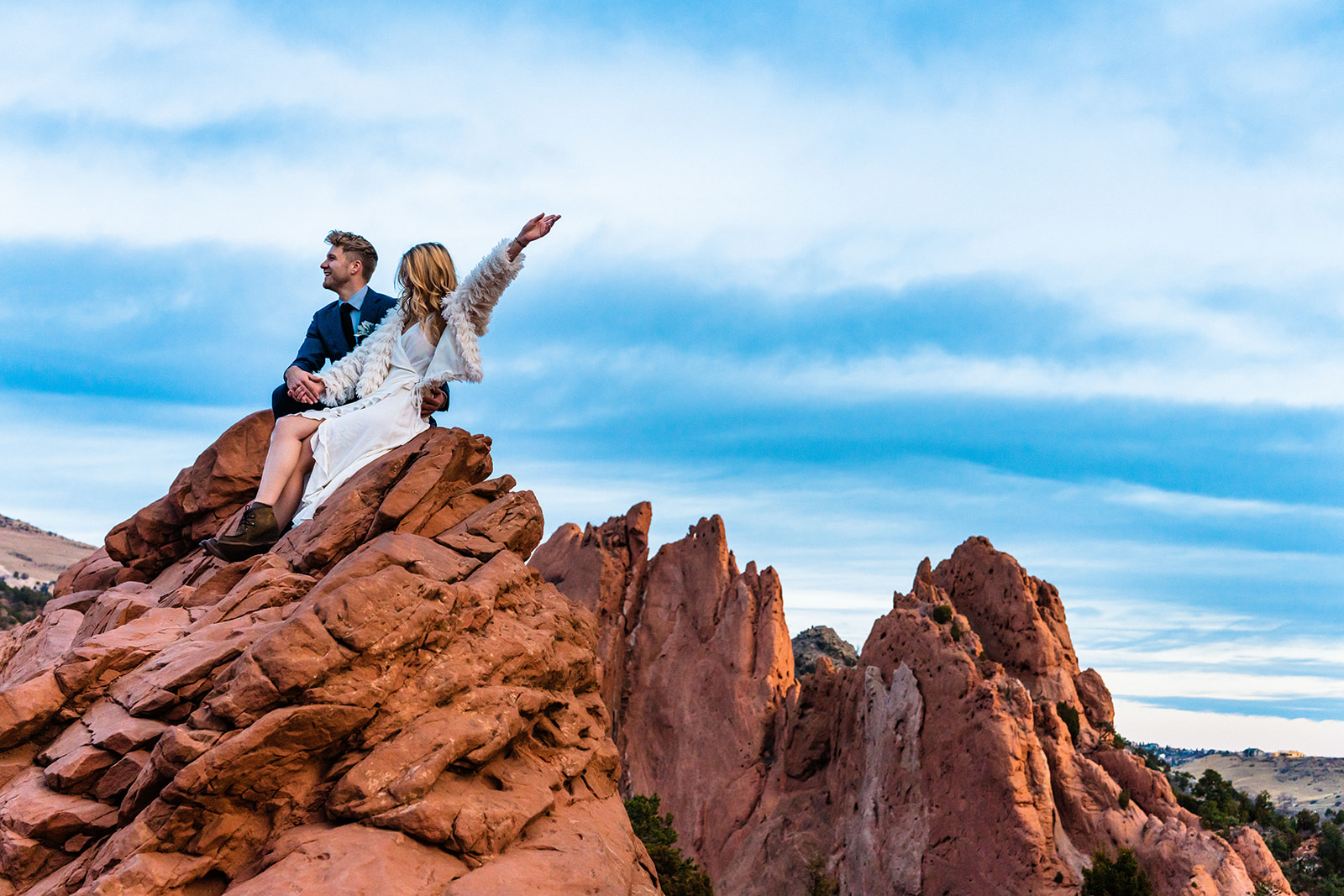 Adventurous couple sitting on top of bright red rocks