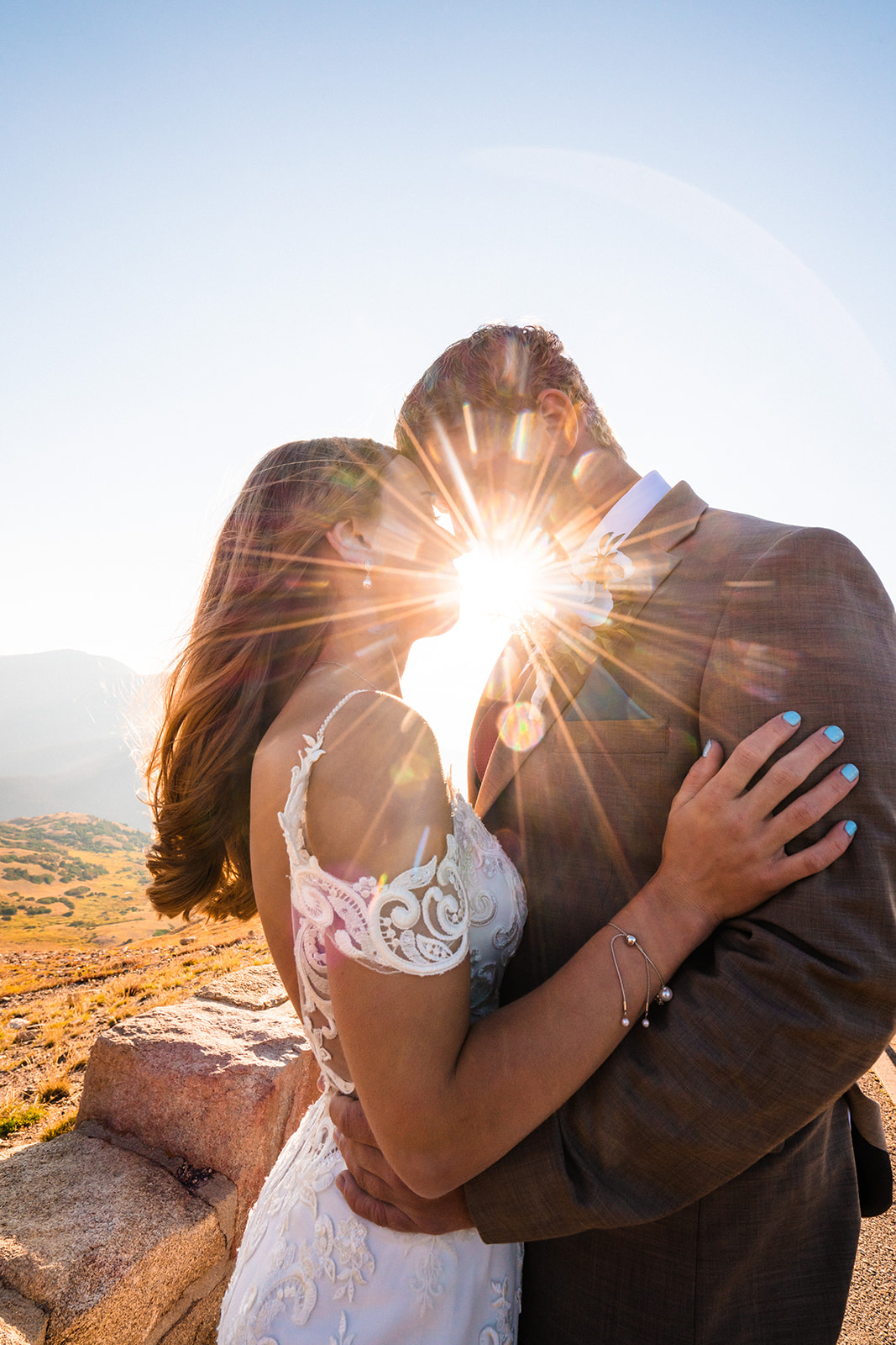 Bride and groom kissing during sunrise