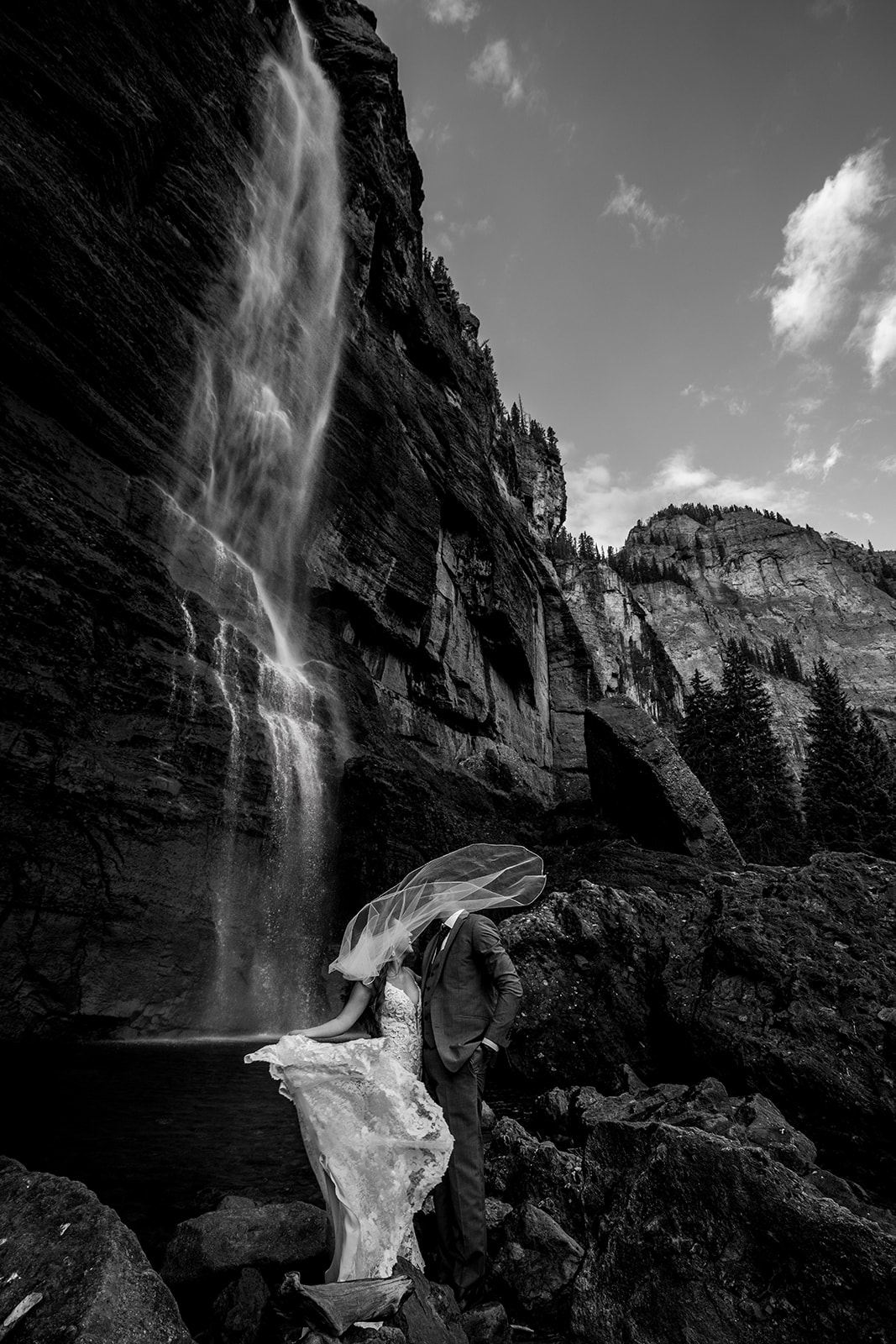 Black and white photo of Bride and groom staring at one another endearingly in front of Bridal Veil Falls