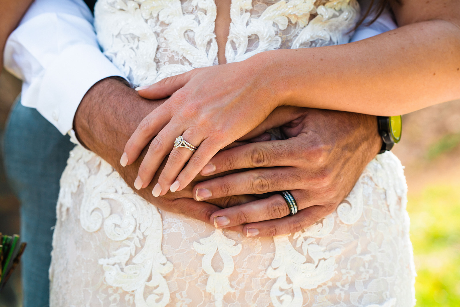 Bride and groom showing off their wedding rings while holding one another