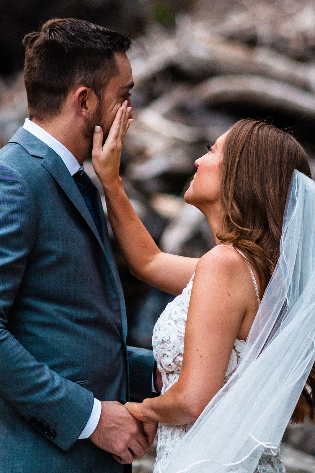 Bride wiping tear off grooms face during first look