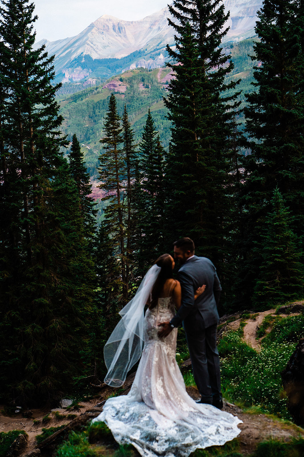 Bride and groom kissing with Colorado mountains and trees in the background