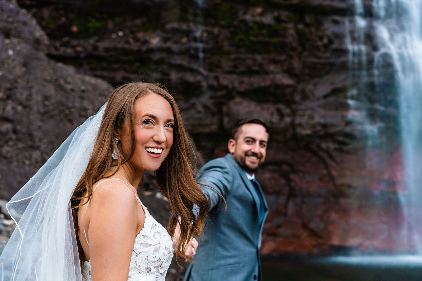 Bride and groom smiling holding hands at Bridal Veil Falls