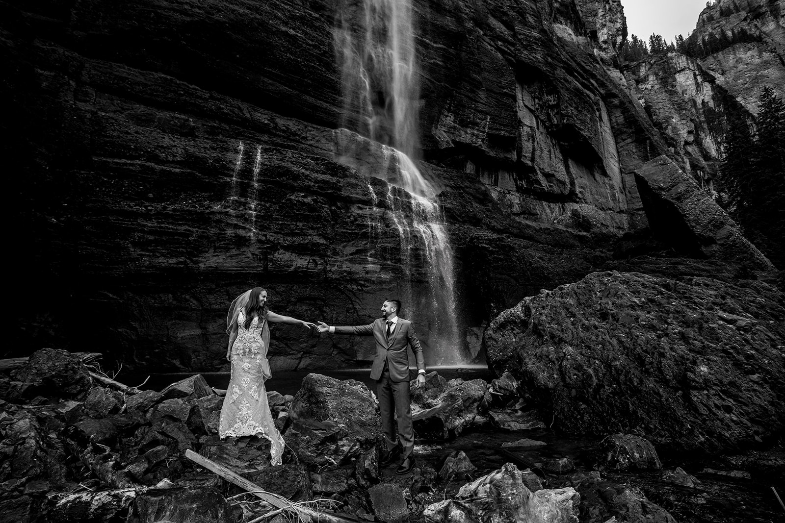 Black and white photo of bride and groom holding hands at Bridal Veil Falls